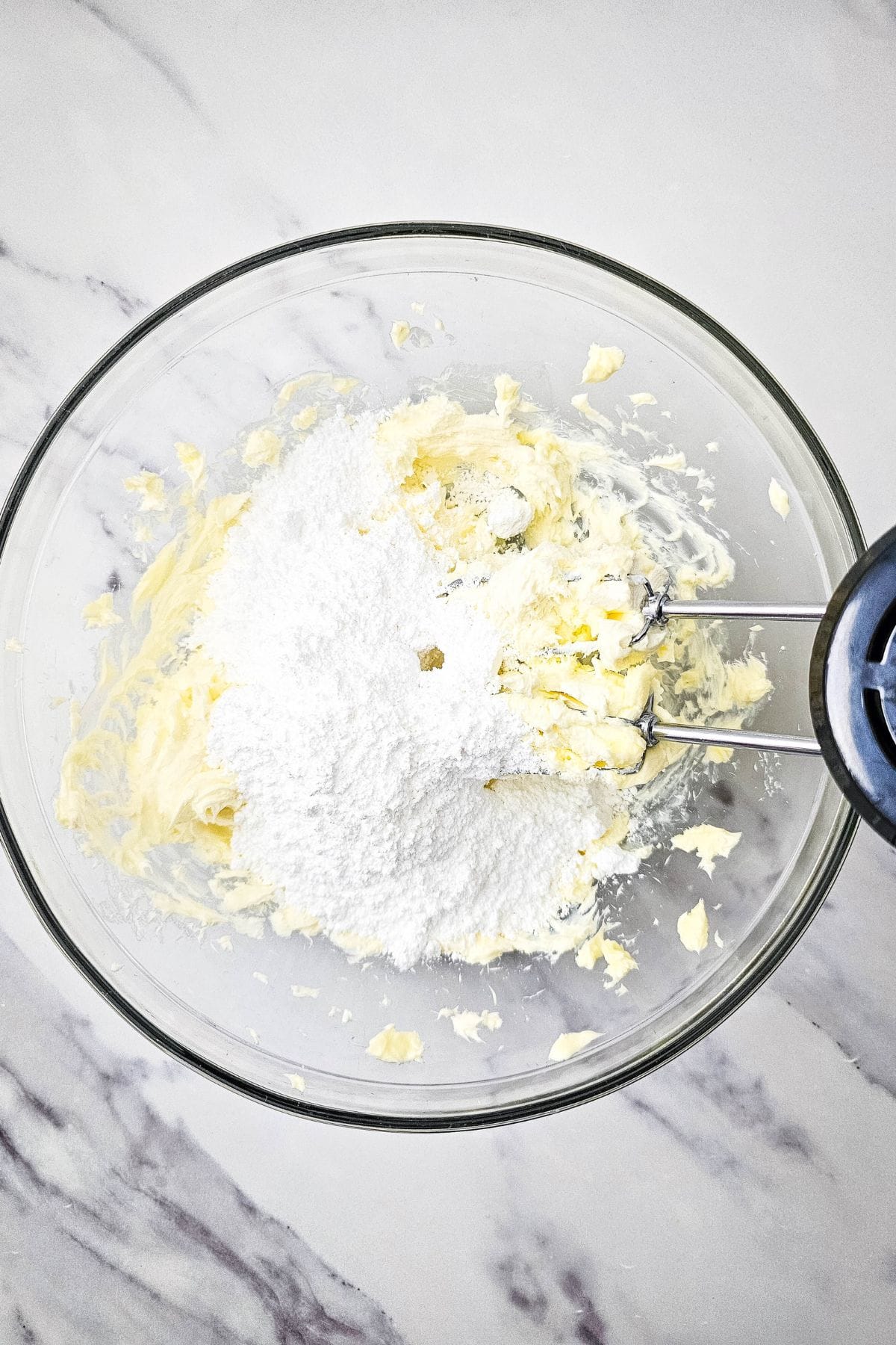 Ingredients for the pineapple filling being mixed together in a bowl with a hand mixer, creating a smooth and creamy texture.
