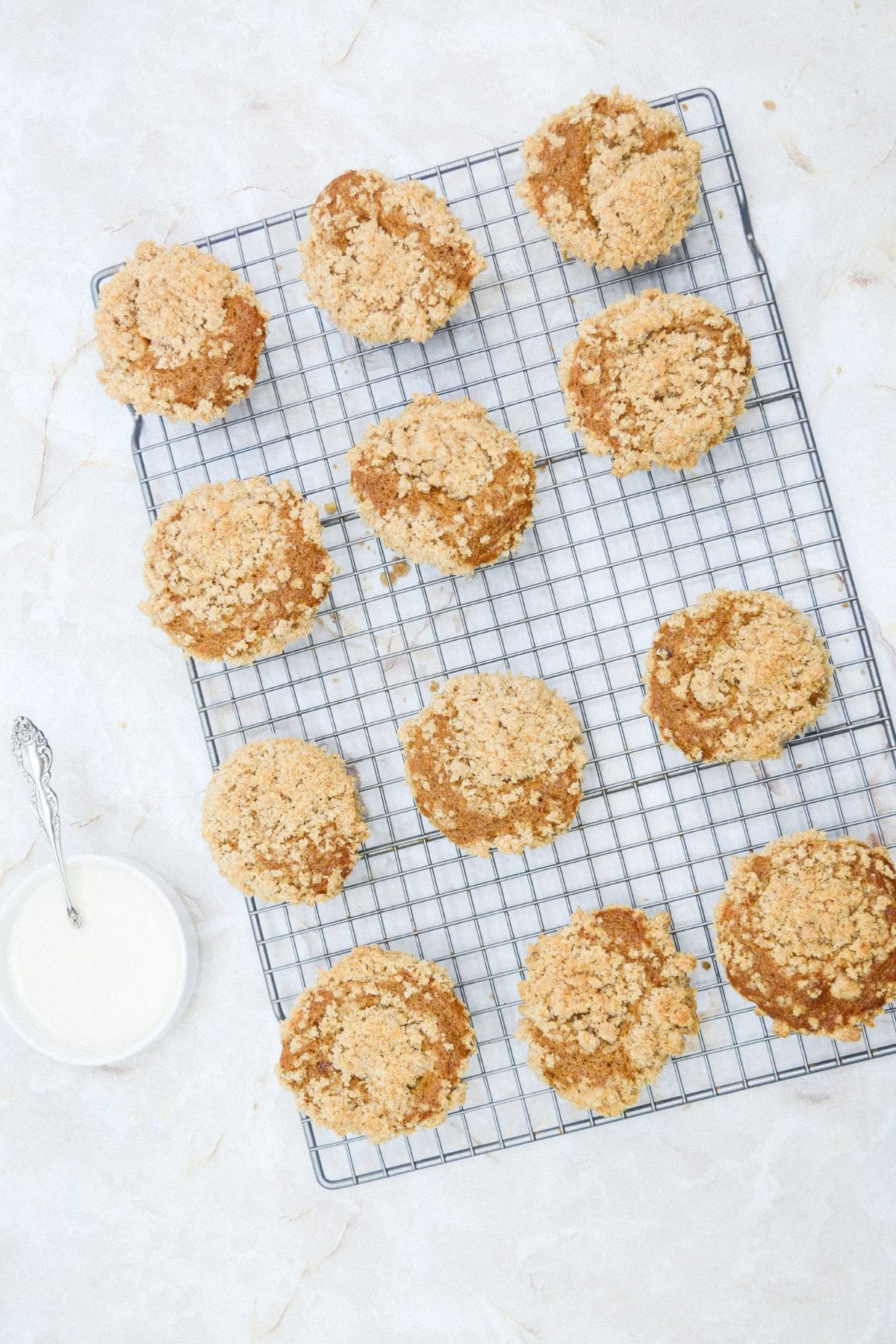 Pumpkin streusel muffins cooling on a wire rack, with golden crumb tops and light glaze setting as they cool.