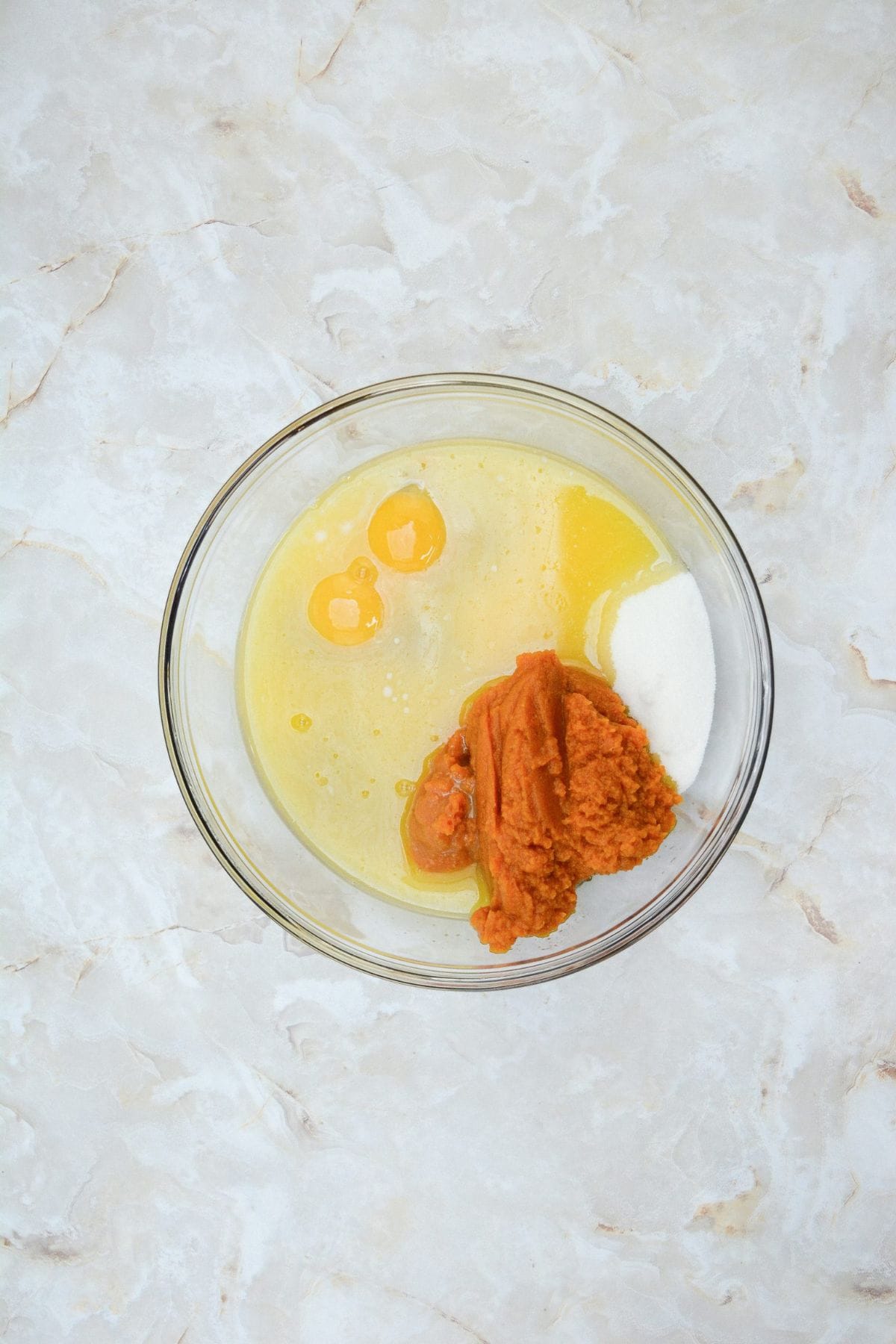 Pumpkin muffin ingredients being mixed together in a large bowl.