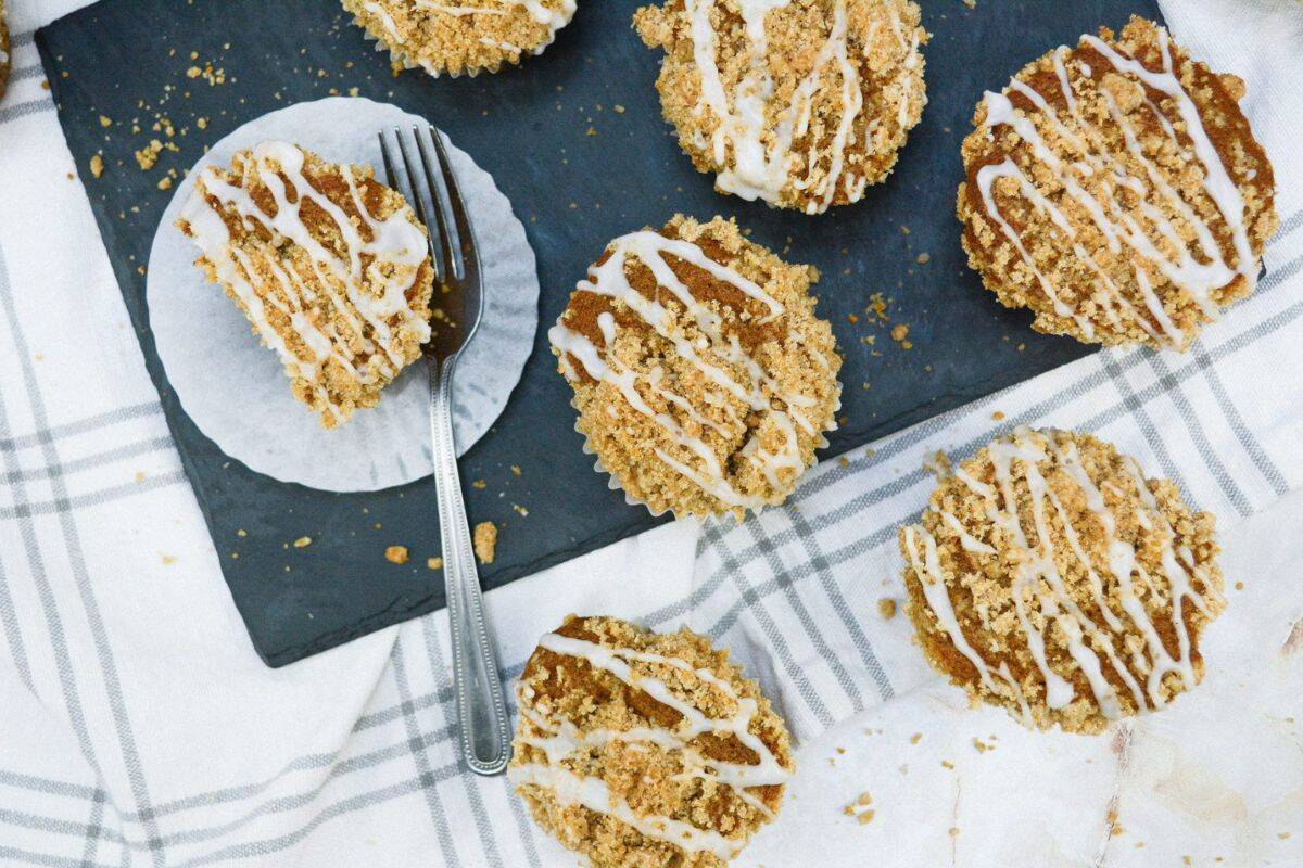 A single pumpkin streusel muffin with a fork beside it, surrounded by more muffins in the background.