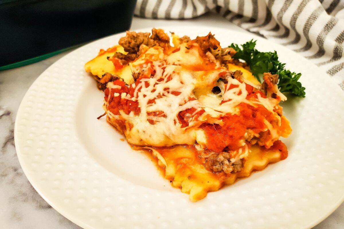 Close-up of ravioli lasagna casserole served on a plate, showing melted cheese and layers of beef and pasta.