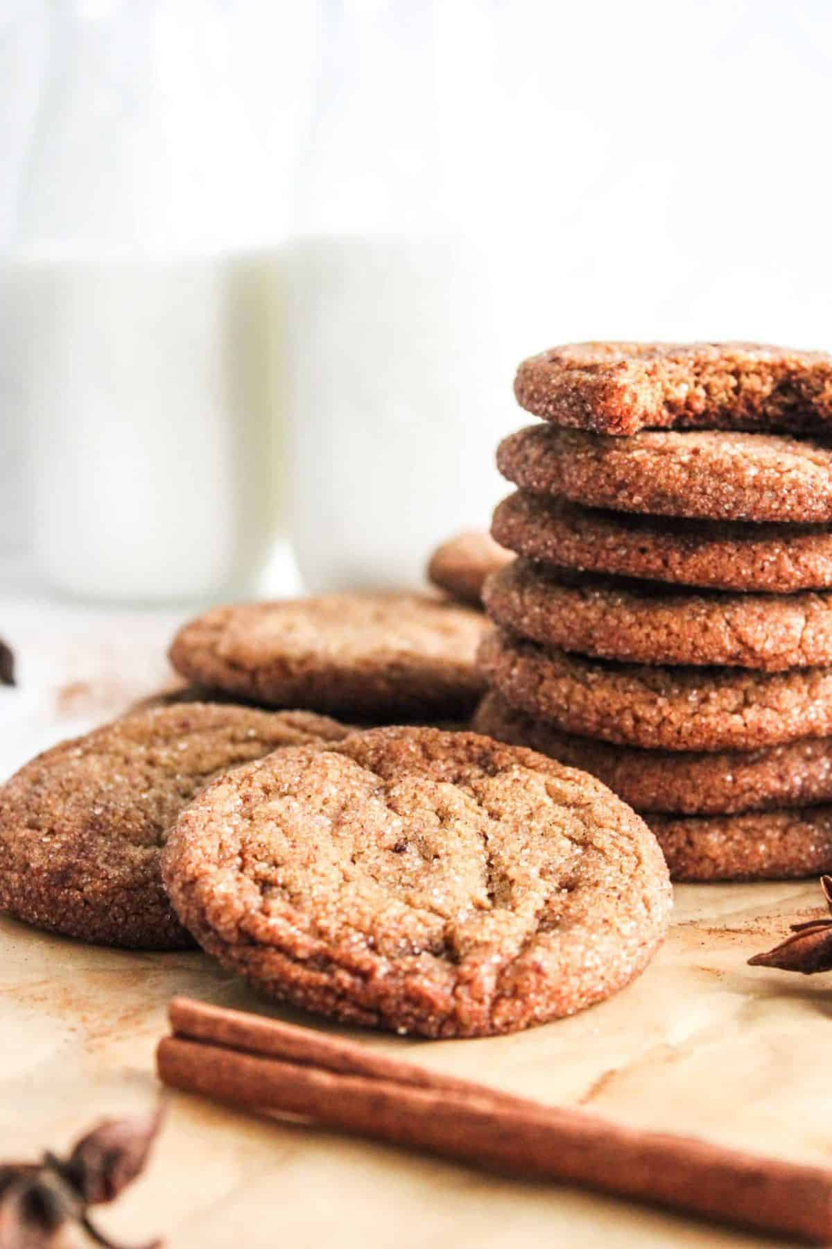 Stack of crisp, spiced gingersnap cookies on a wooden board, showing their golden-brown edges.