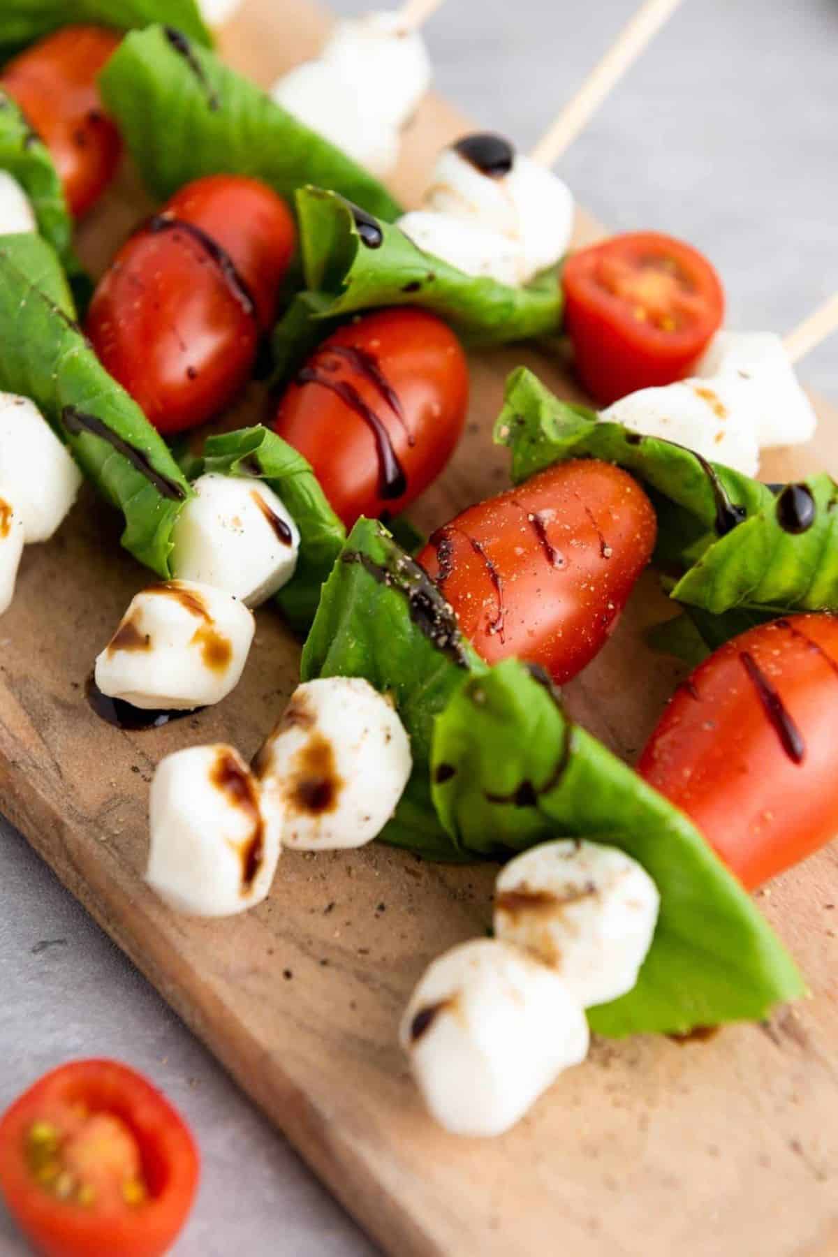 Caprese salad skewers arranged on a wooden board.