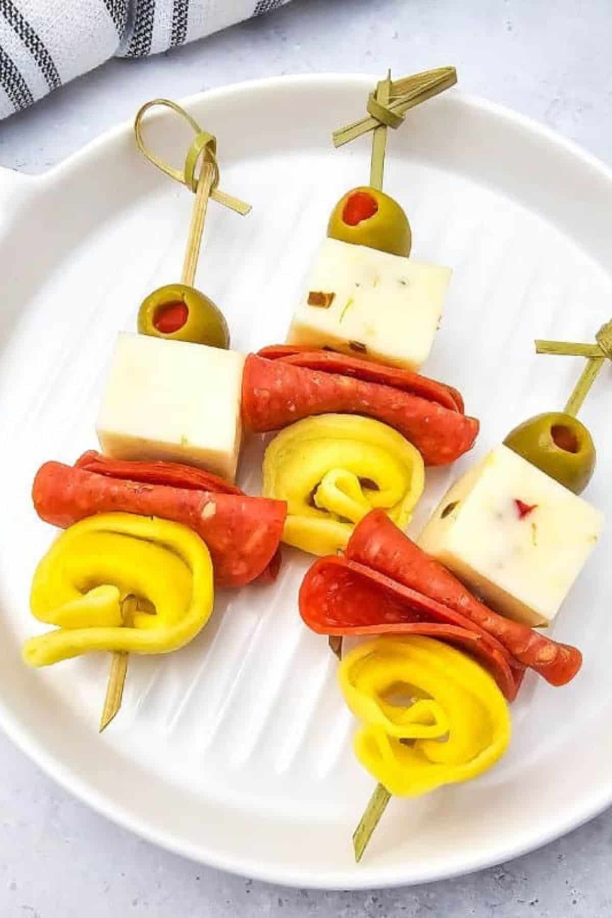 Tortellini skewers with pepperoni and olives arranged neatly on a serving plate.