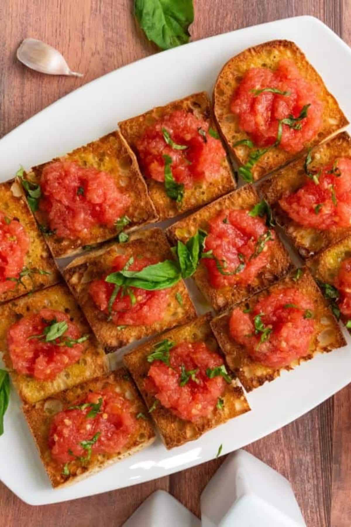 A plate with Spanish Pan con Tomate tapas, showing toasted bread topped with tomato and olive oil.