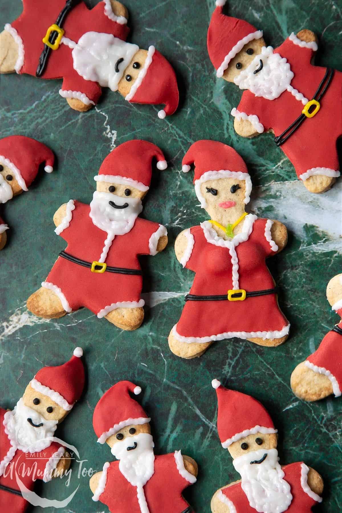 anta Christmas Cookies arranged on a green surface, decorated with sugar paste to resemble jolly Santas.