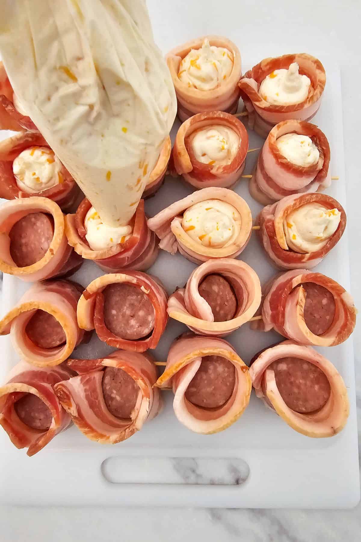 Bacon-wrapped pig shot being filled with a cheese mixture.