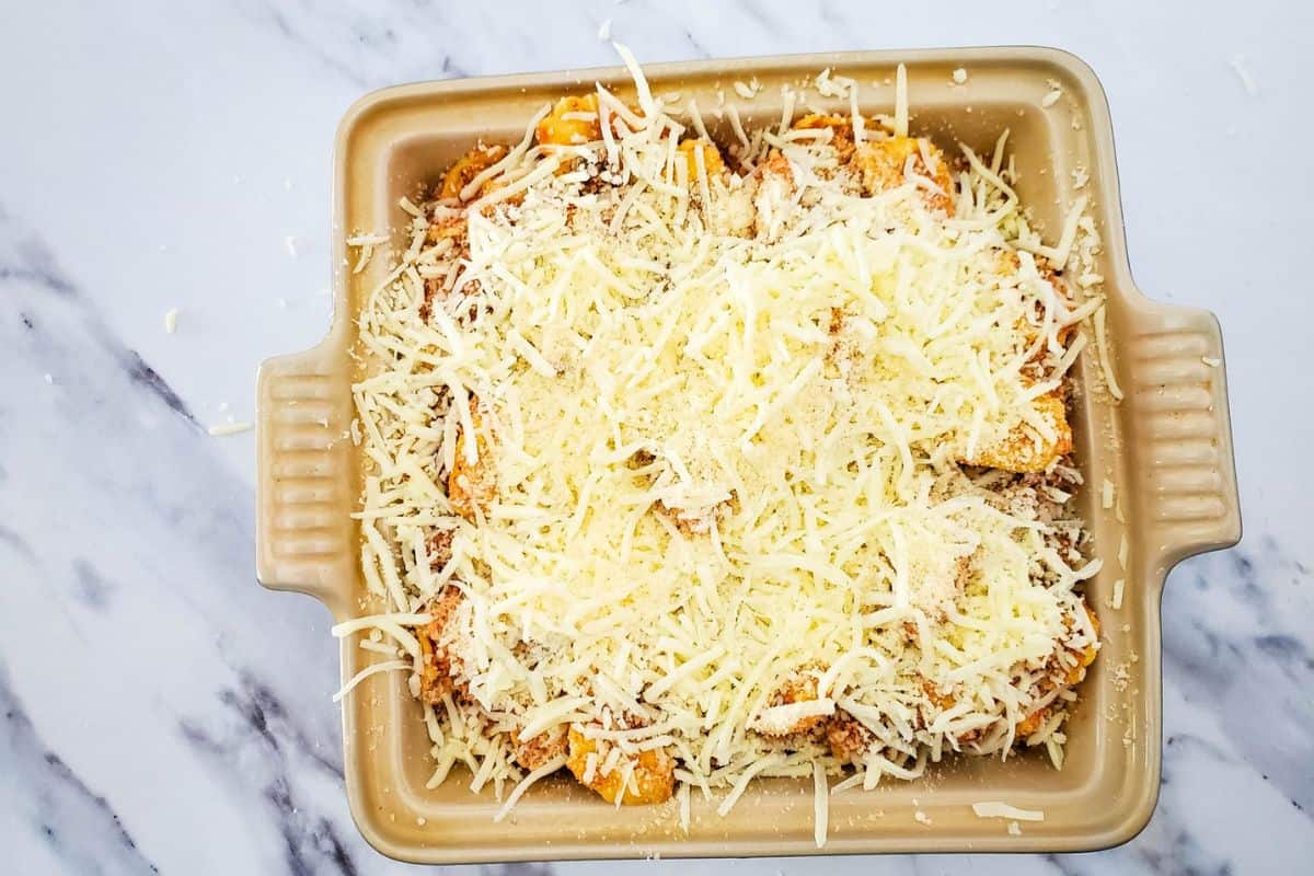 Cheese-topped tortellini in a baking dish, ready for baking.