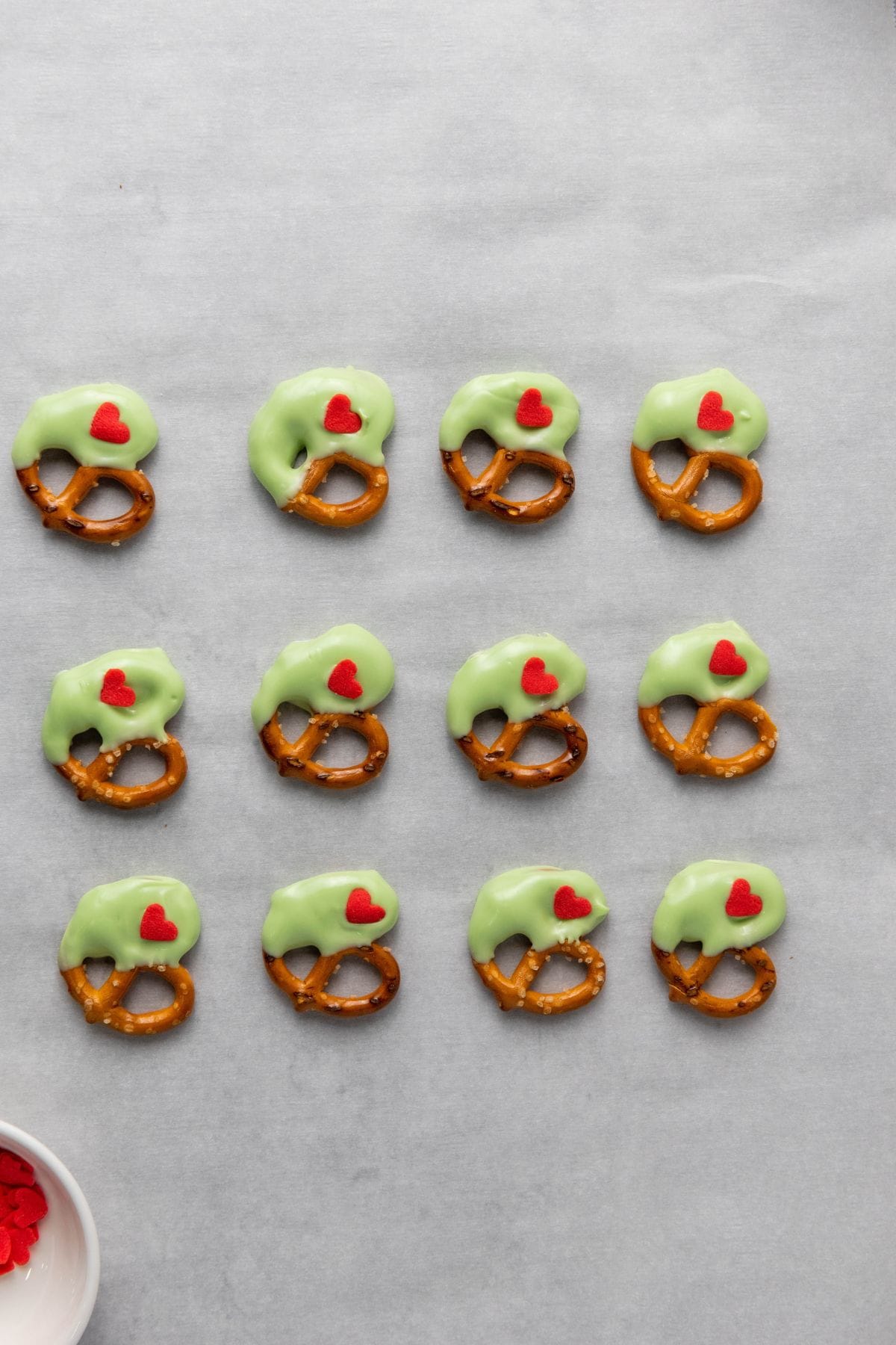 Pretzels dipped in green candy melts and topped with red heart sprinkles.