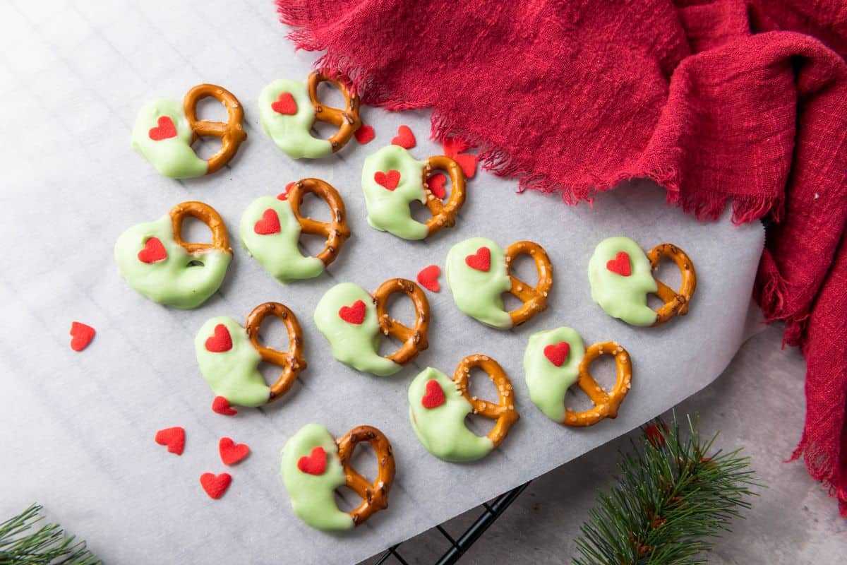 Christmas pretzels on a surface surrounded by heart sprinkles and a red cloth.