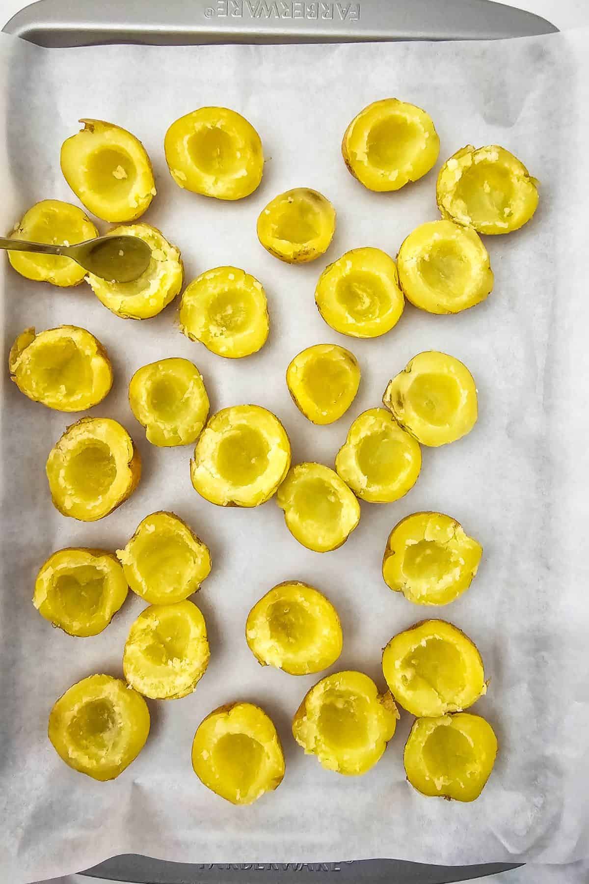 Halved baby potatoes placed on a parchment-lined baking tray.