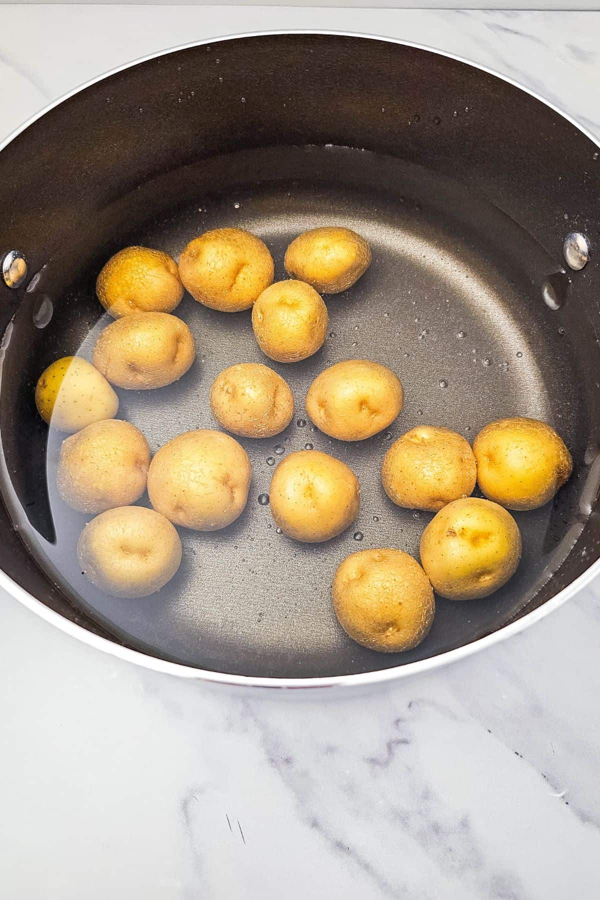 Baby potatoes soaking in water inside a pot.