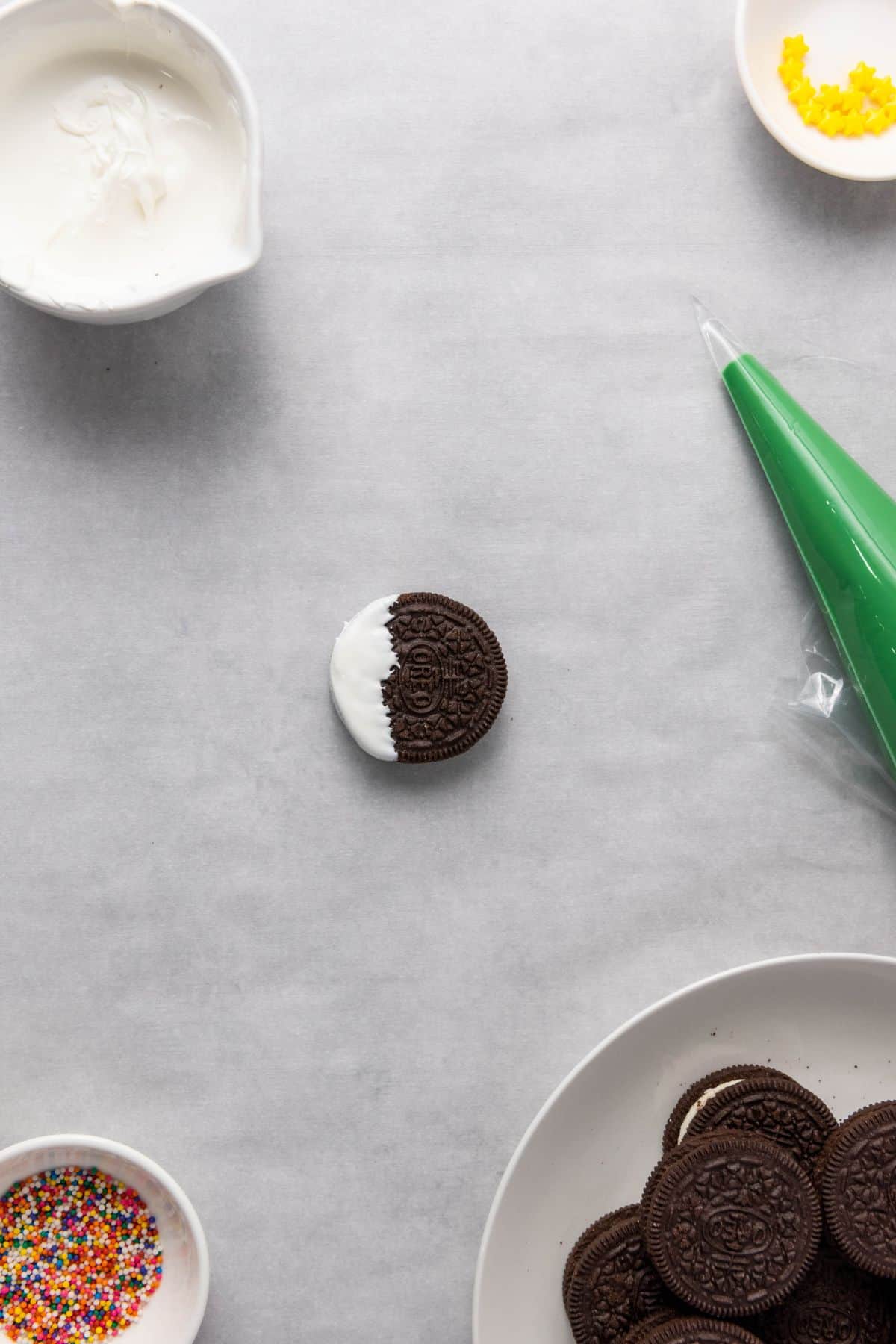 Single Oreo being dipped into white frosting placed on a surface.