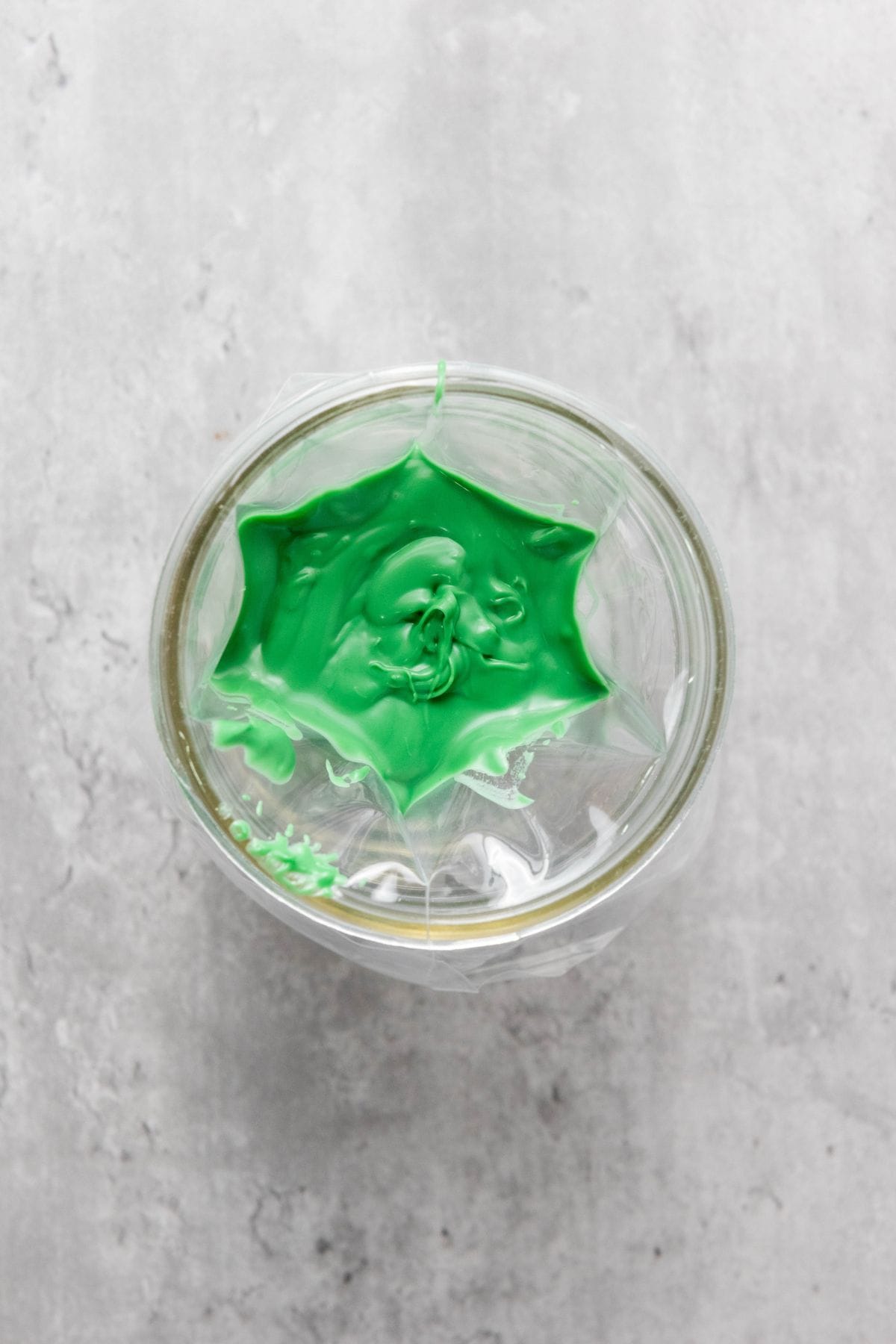 Green frosting in a glass with a piping bag ready for decorating.