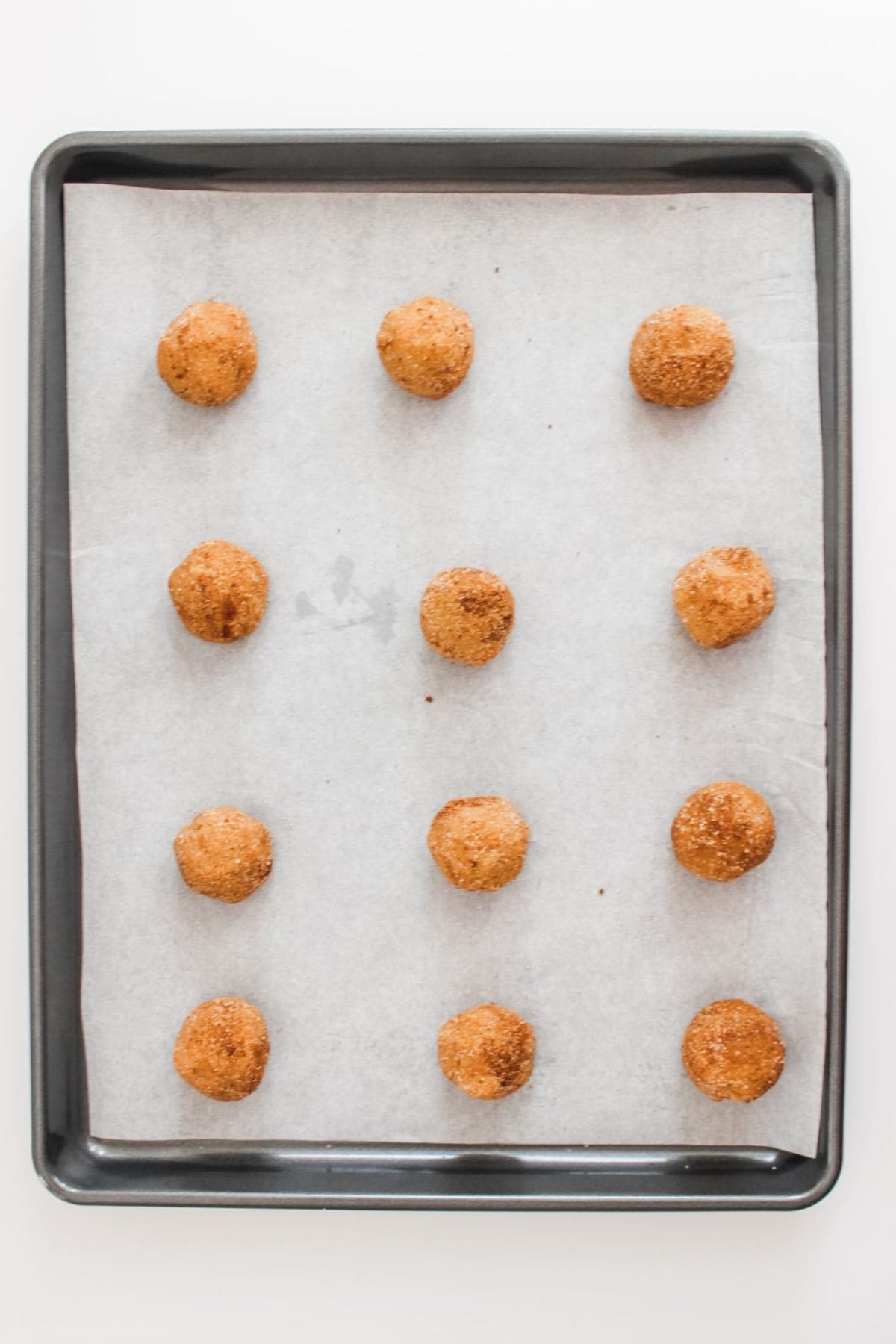 Baking pan with parchment paper and scooped batter ready to bake.