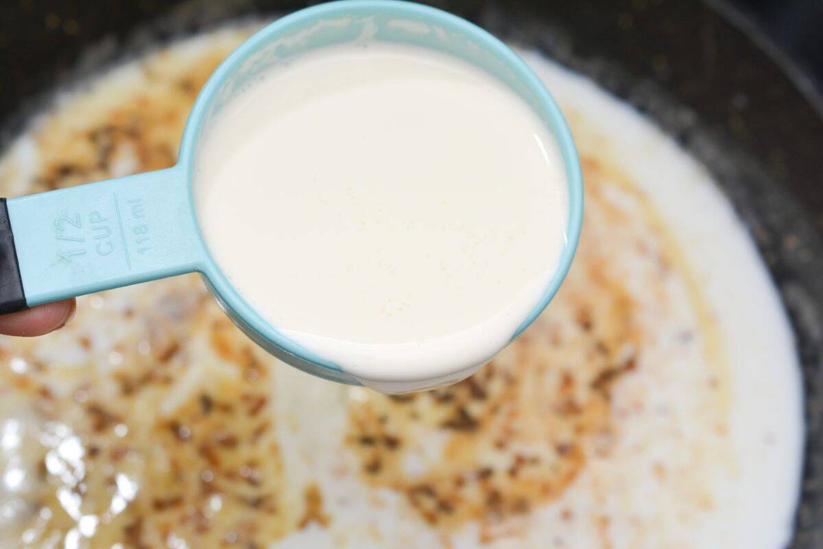 Measuring spoon with milk being added to the pot.