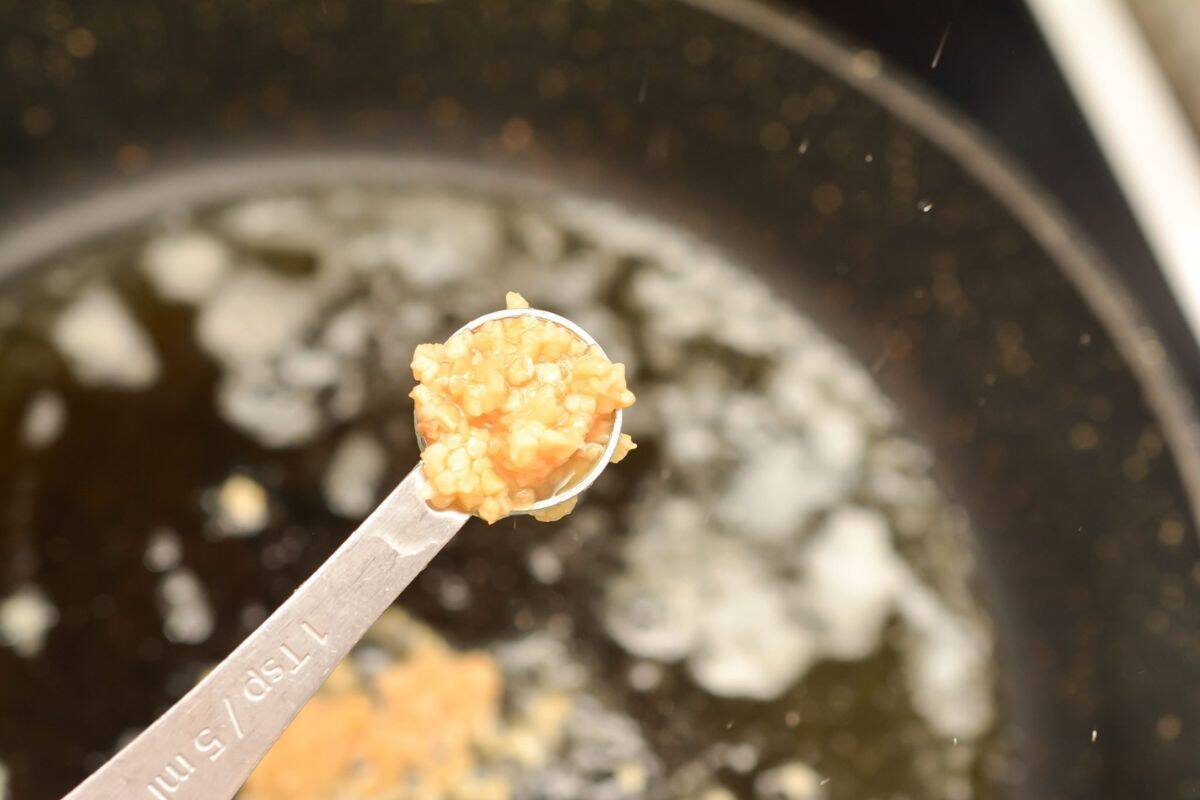 Pouring garlic powder and herbs into the sauce mixture in a large pot.