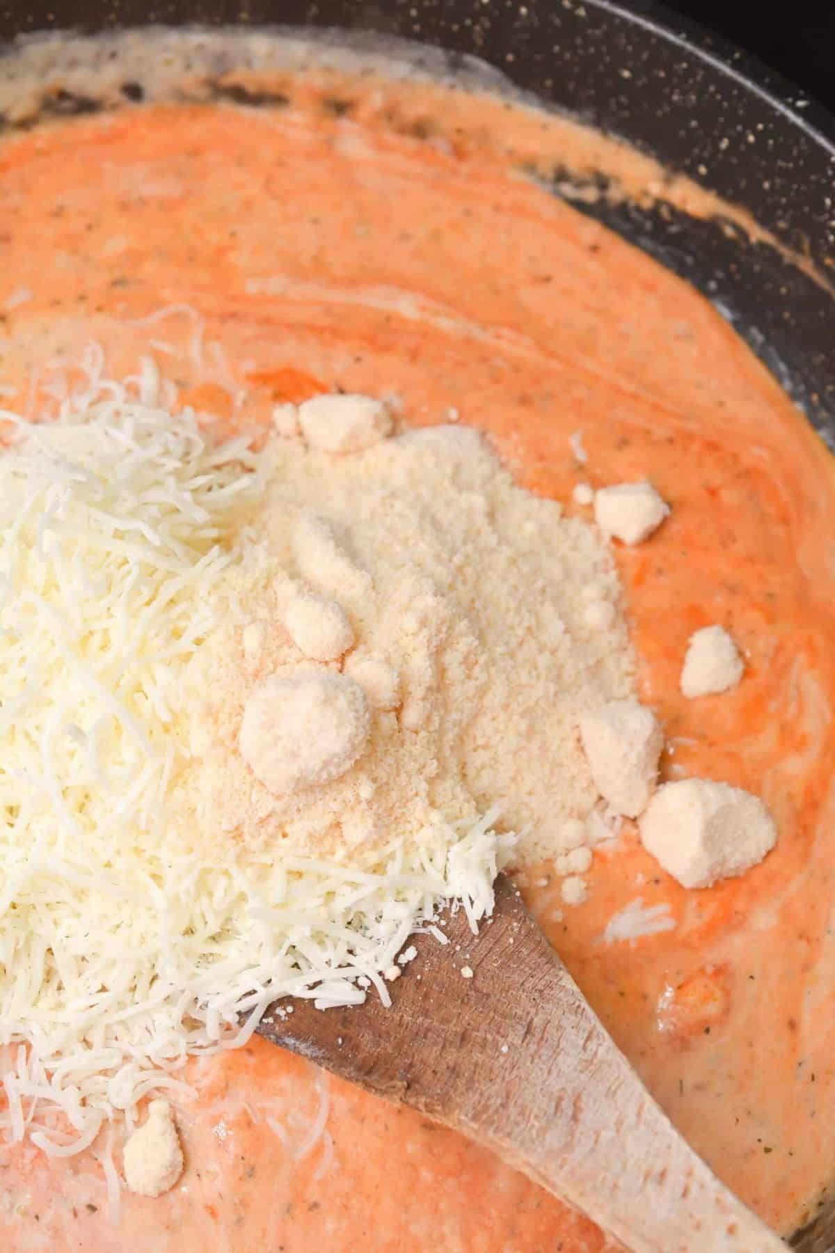 Cheese powder being added to sauce in a large pot.