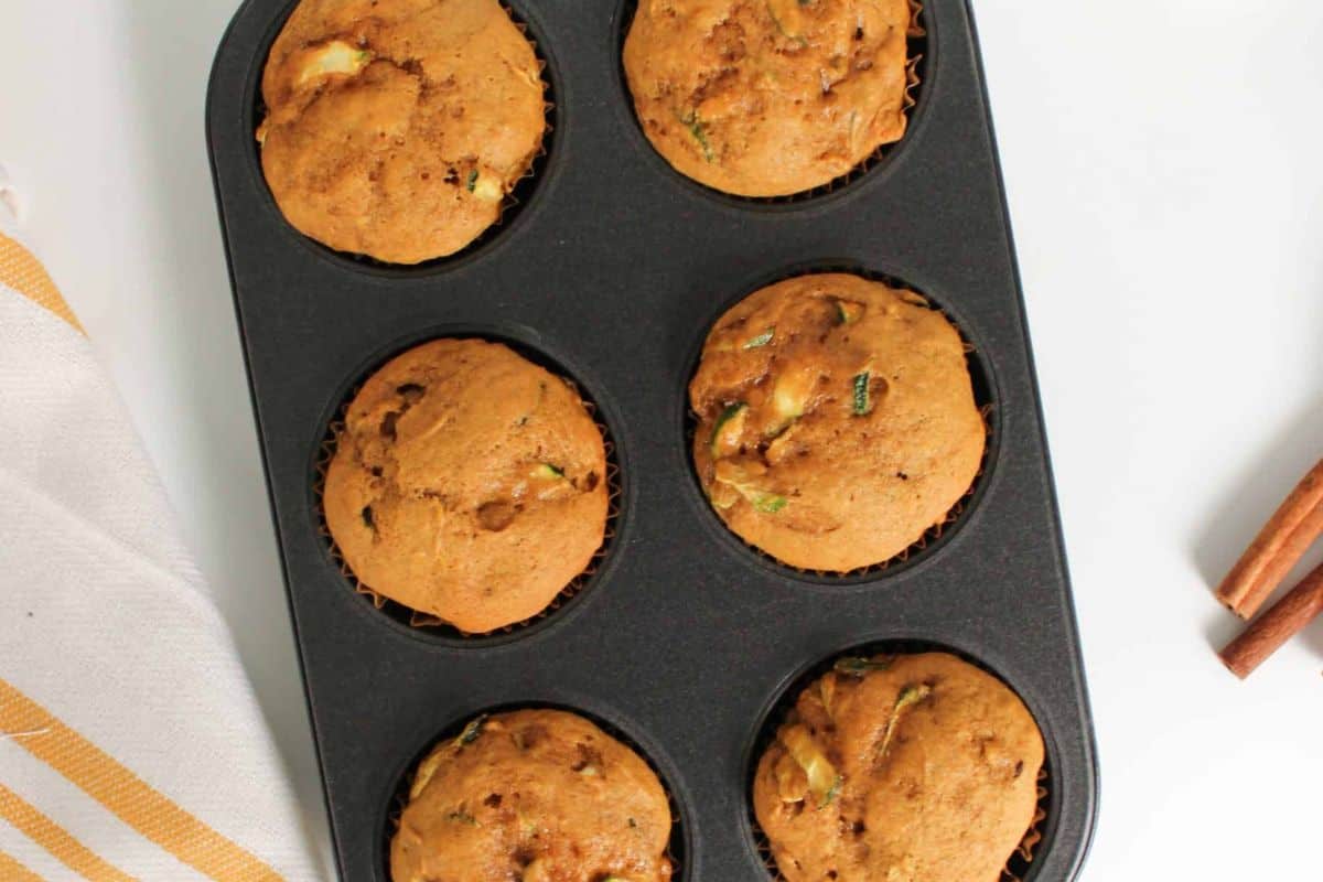 Freshly baked zucchini muffins still warm in a muffin tin.