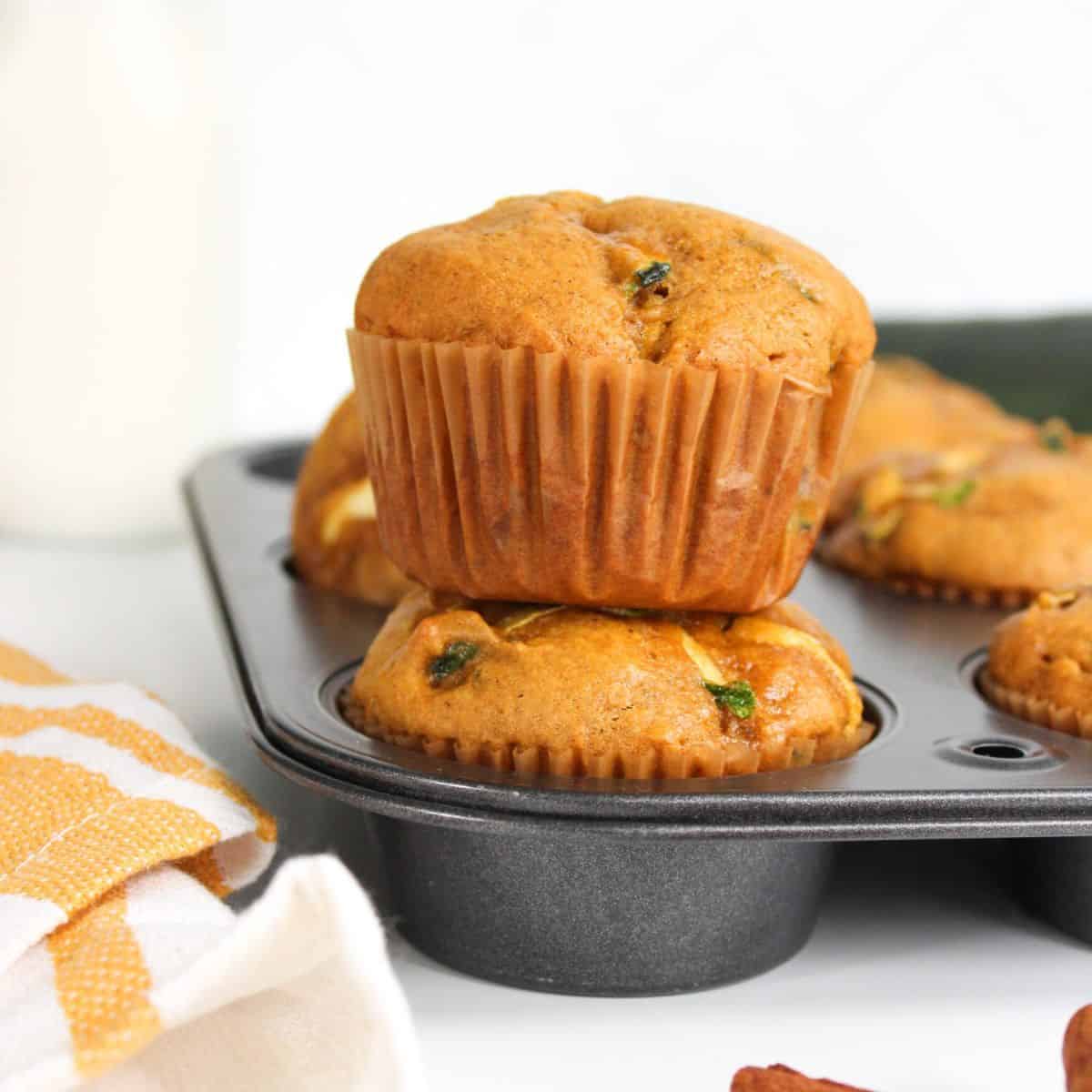 Freshly baked muffins stacked on top of each other in a muffin tin.