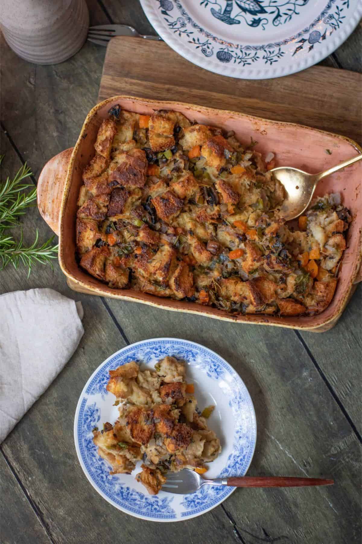 Herb and vegetable stuffing in a serving dish with a serving spoon, plated portion showing seasoned vegetables and golden, crispy top.