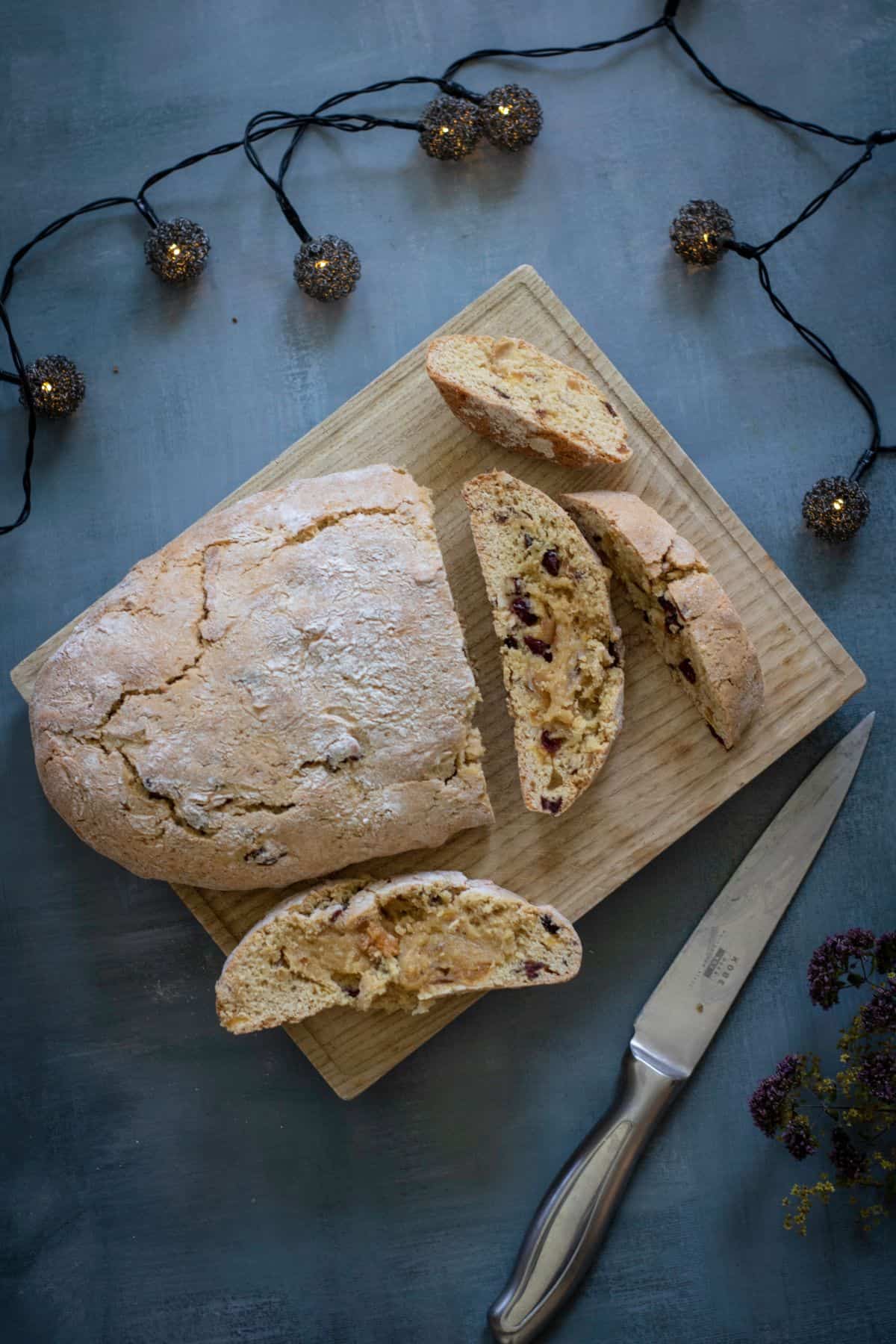 Freshly baked dough placed on a wooden board being sliced.