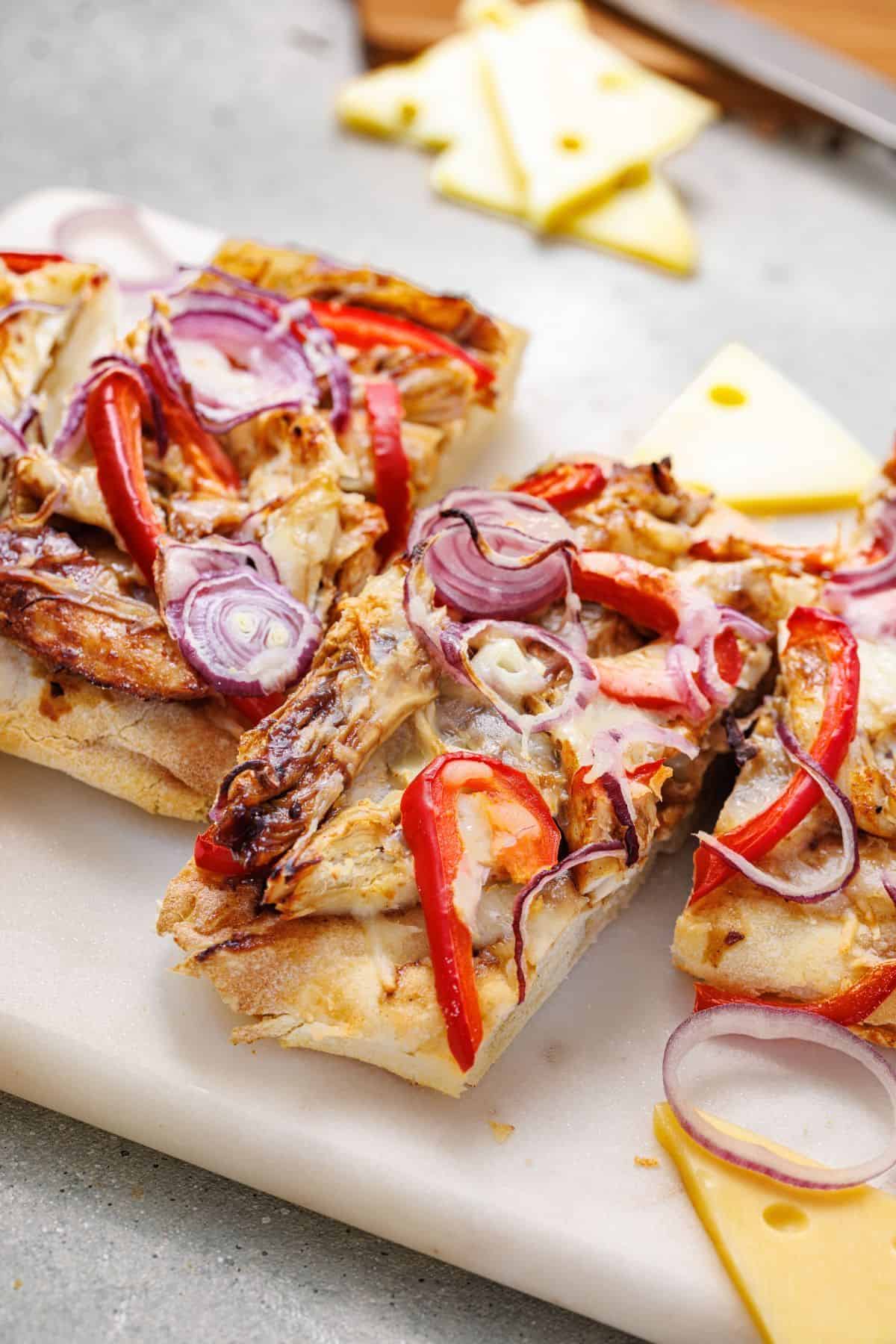 Sliced chicken flatbread topped with grilled chicken pieces, fresh tomatoes, and onions.