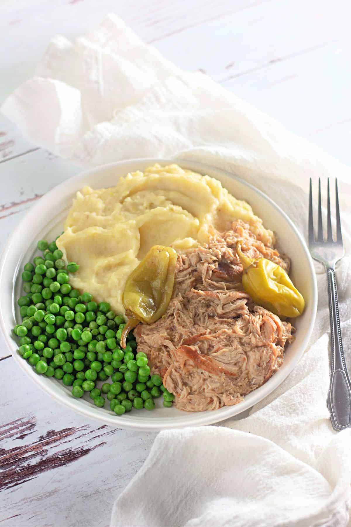 Tender Slow Cooker Mississippi Chicken served in a bowl with a fork on the side.
