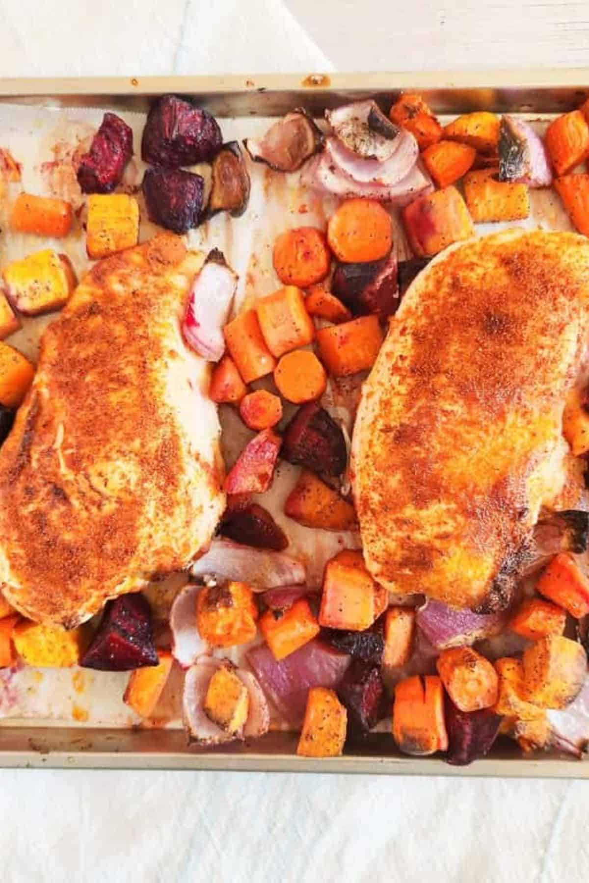 One pan roasted chicken in a serving dish with colorful vegetables like carrots, broccoli, and bell peppers