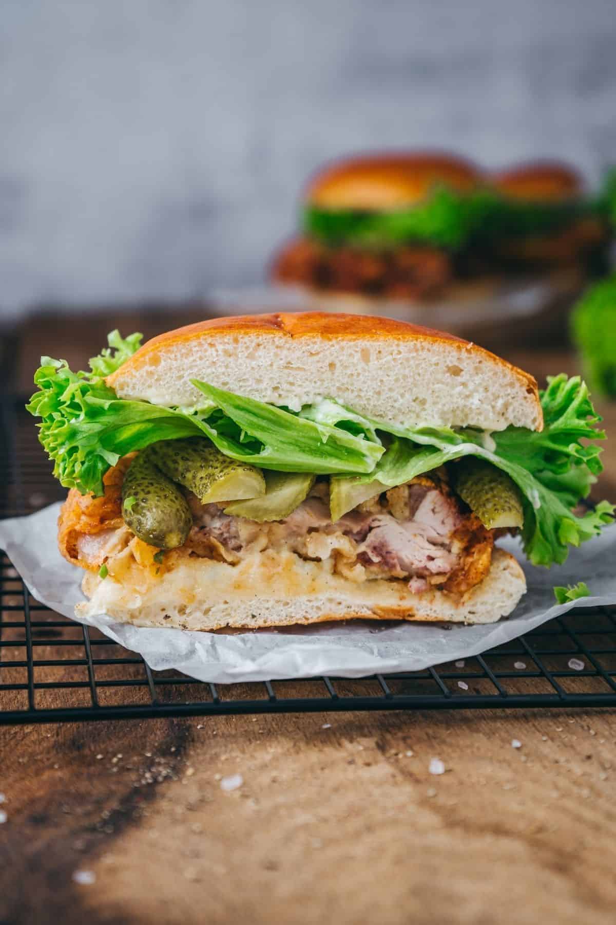 Close-up of a crispy buttermilk fried chicken sandwich with golden breading and fresh toppings.