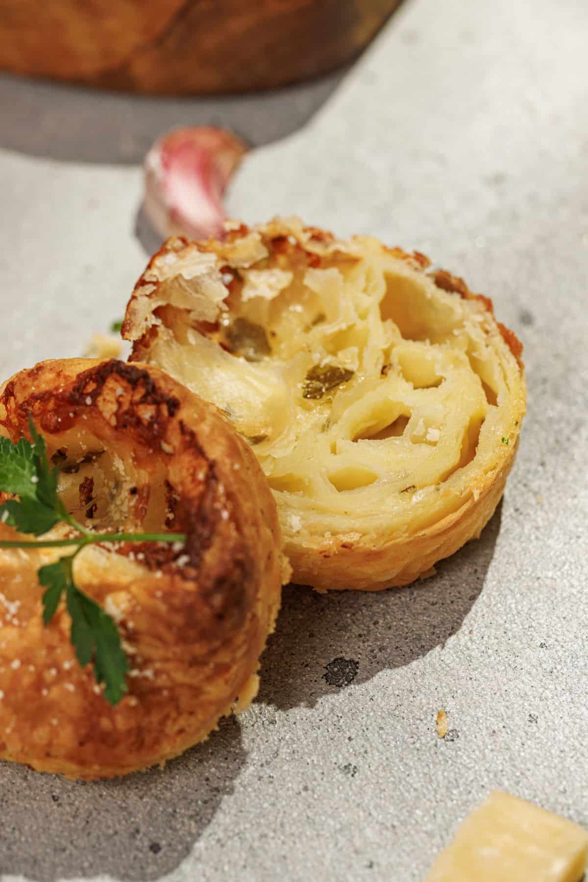 Cheesy Garlic Cruffins being sliced in the center, revealing the soft, airy layers and gooey melted cheese inside.