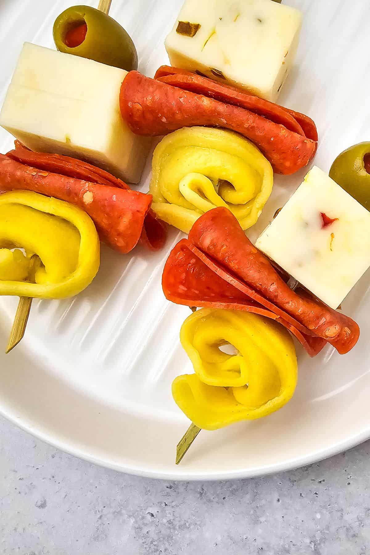 Close-up of tortellini skewers with pepperoni and olives arranged in a serving dish.