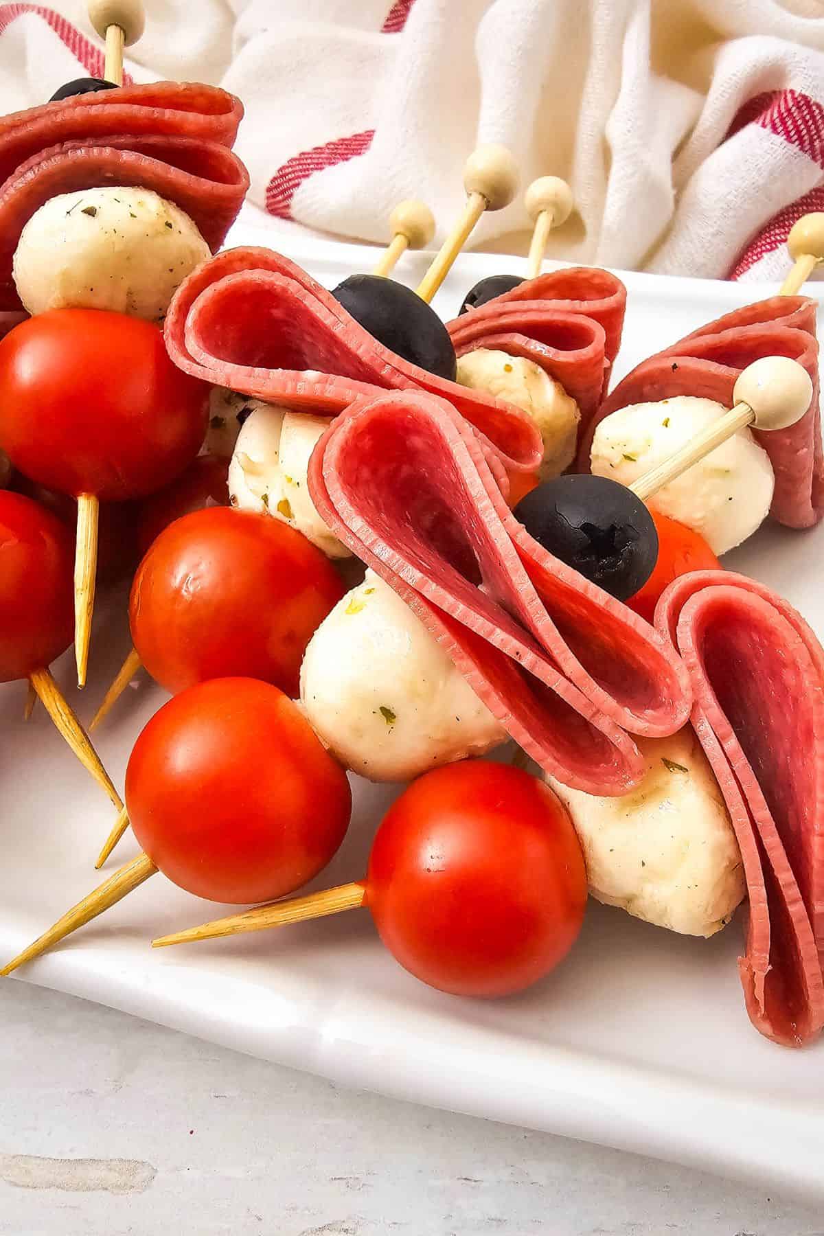 Close-up of colorful antipasto skewers with salami, olives, mozzarella, and cherry tomatoes.