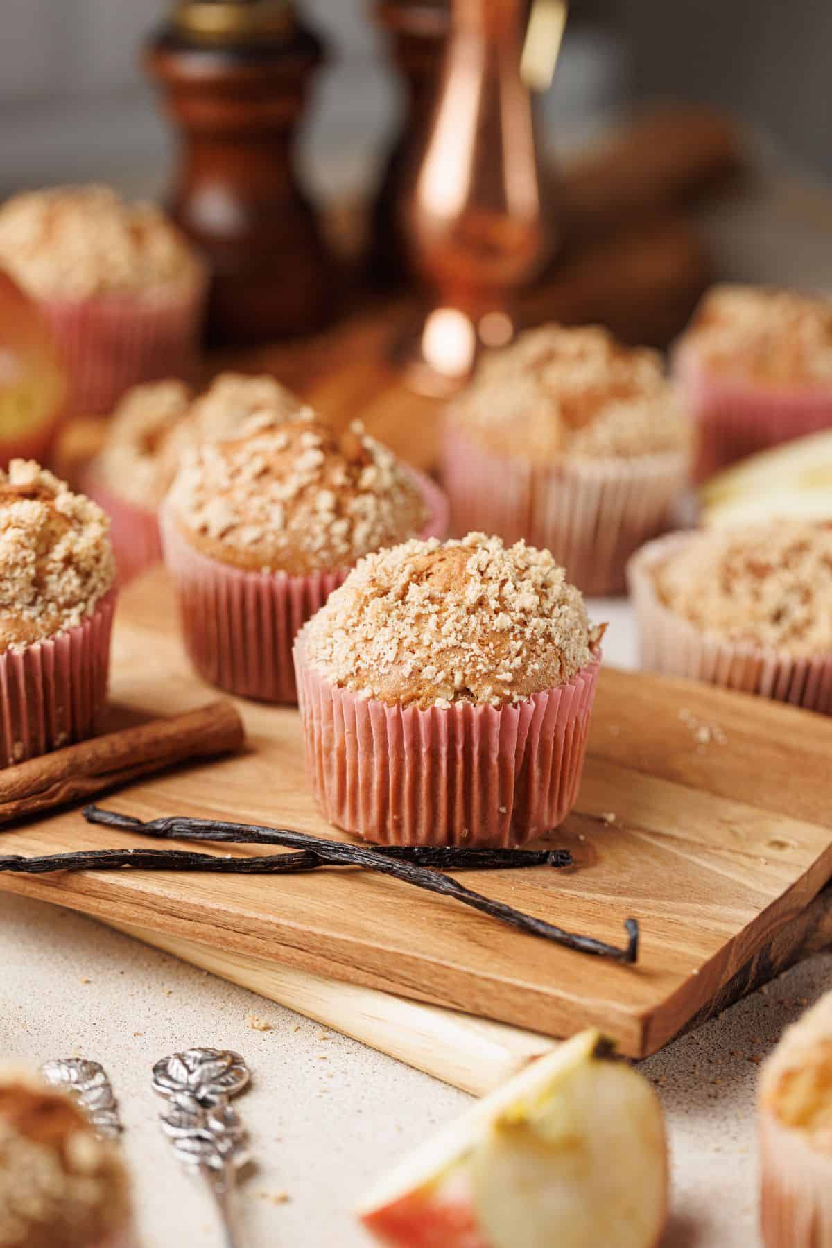 Apple cinnamon muffins served on a wooden board.
