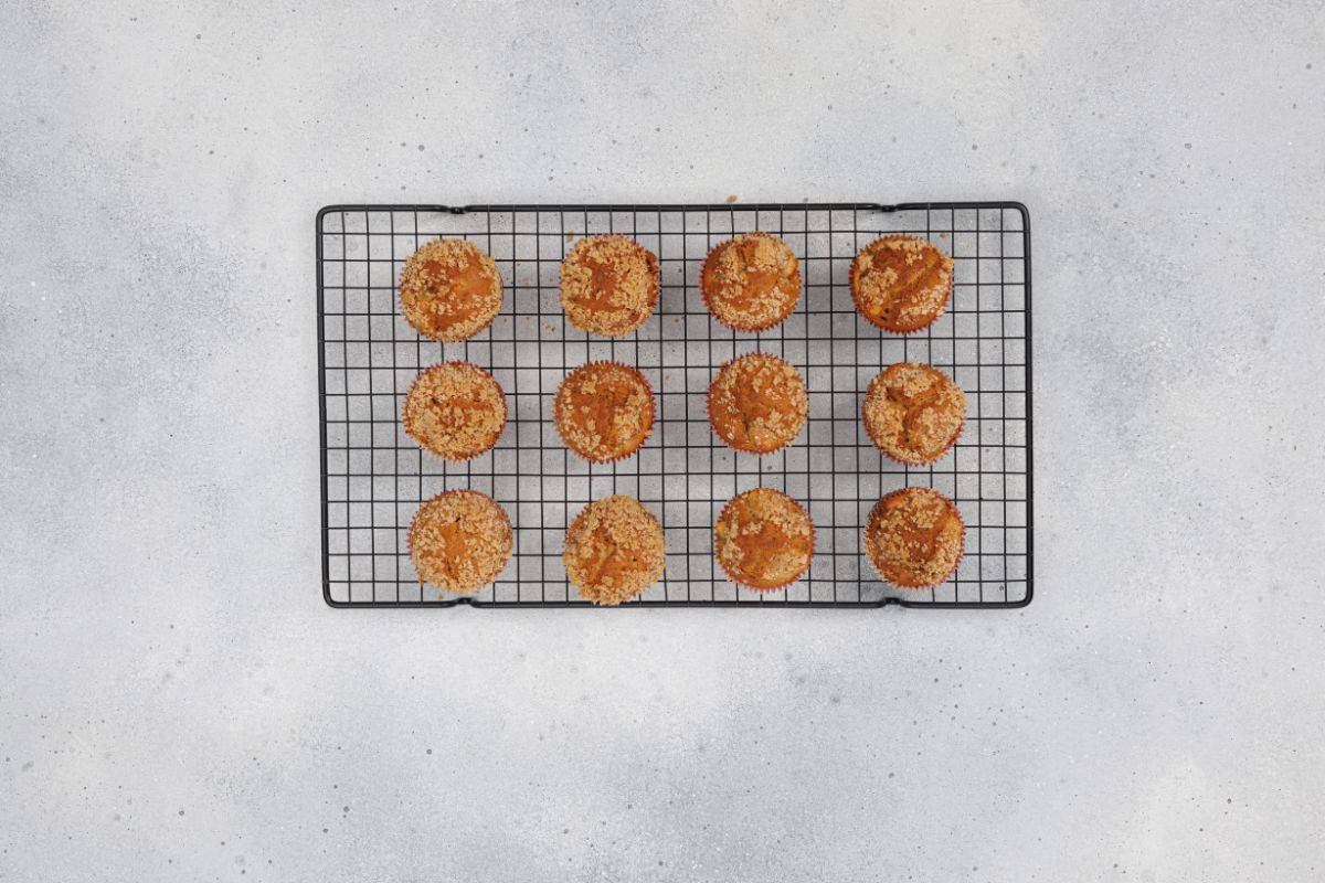 Freshly baked apple cinnamon muffins resting on a cooling wire rack.