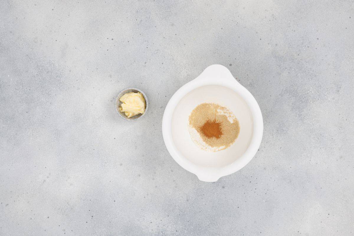 Cream and spices in a white bowl with butter on a gray background.