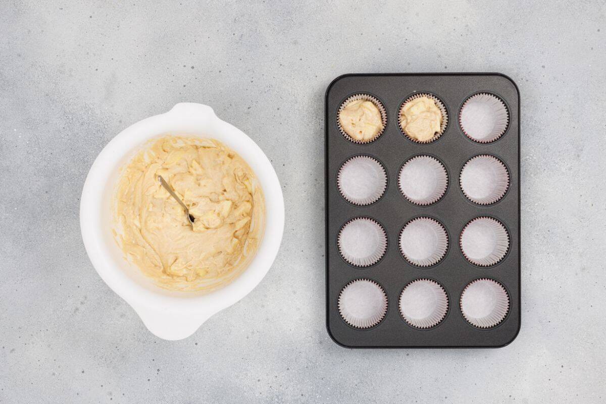 Mixture in a bowl with a tin can holding a scooped portion of the apple muffin mixture.