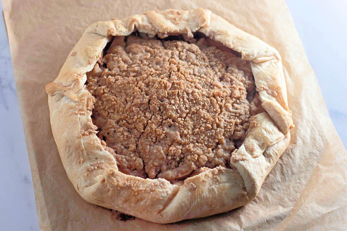 Whole baked Apple Galette placed on a wooden cutting board.