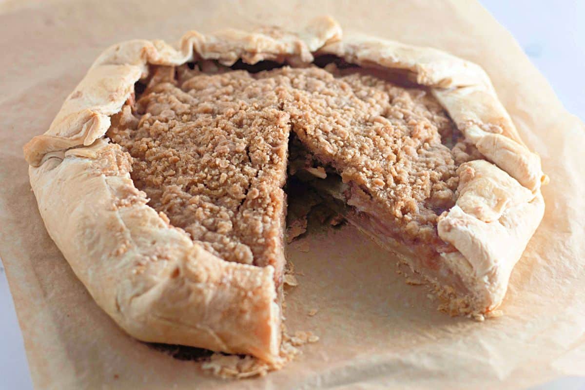 Baked Apple Galette being sliced on a wooden cutting board.