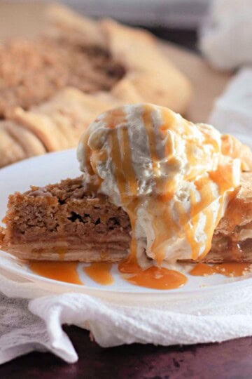 Sliced Apple Crumb Galette served on a plate with a scoop of vanilla ice cream, with the remaining galette visible in the background.