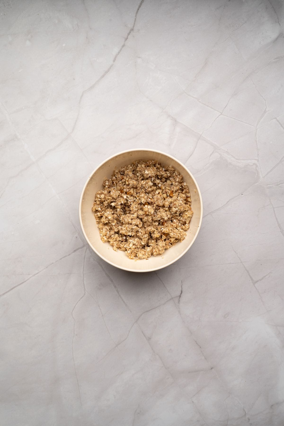 A small bowl containing the topping mixture for apple crisp.