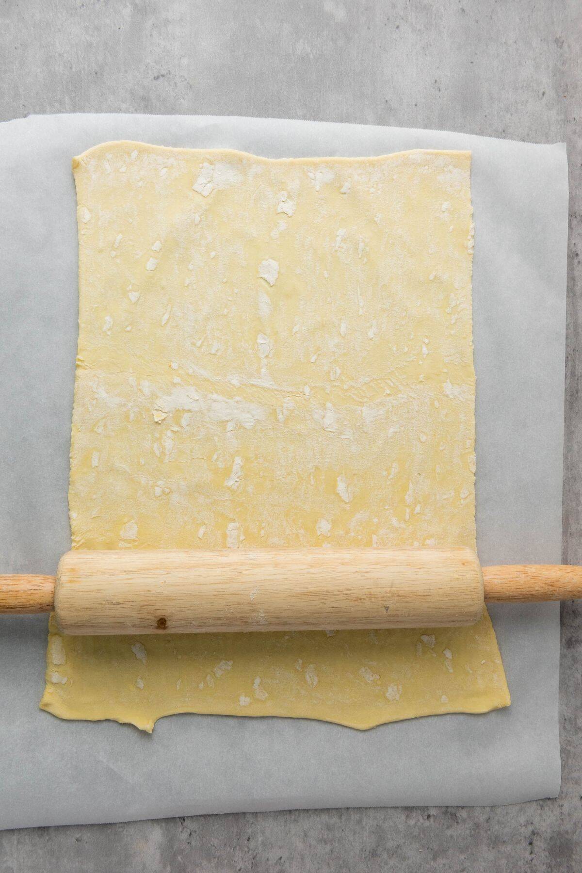 Dough being flattened on lightly floured parchment paper.