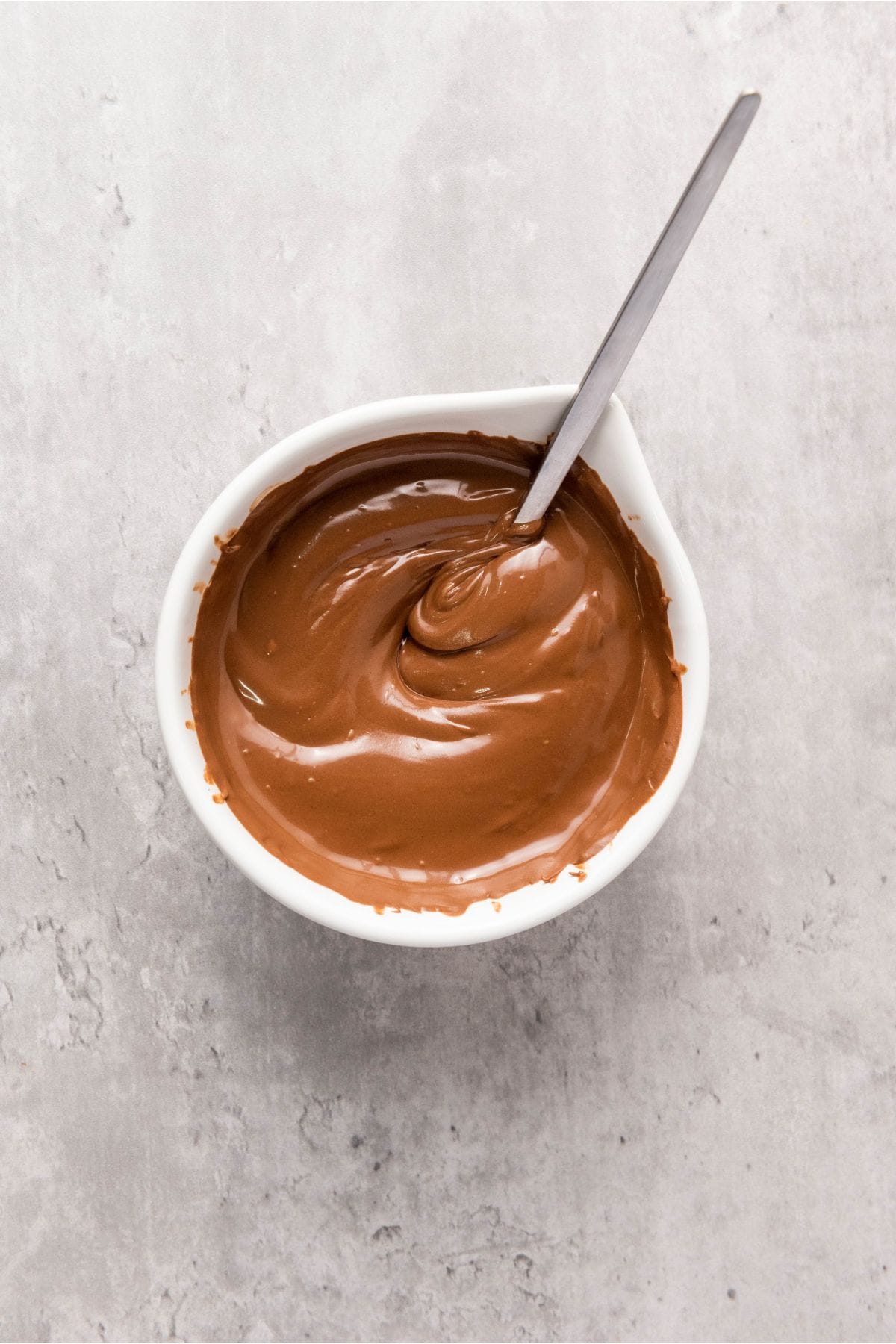 Melted chocolate in a small bowl with spoon resting on it.