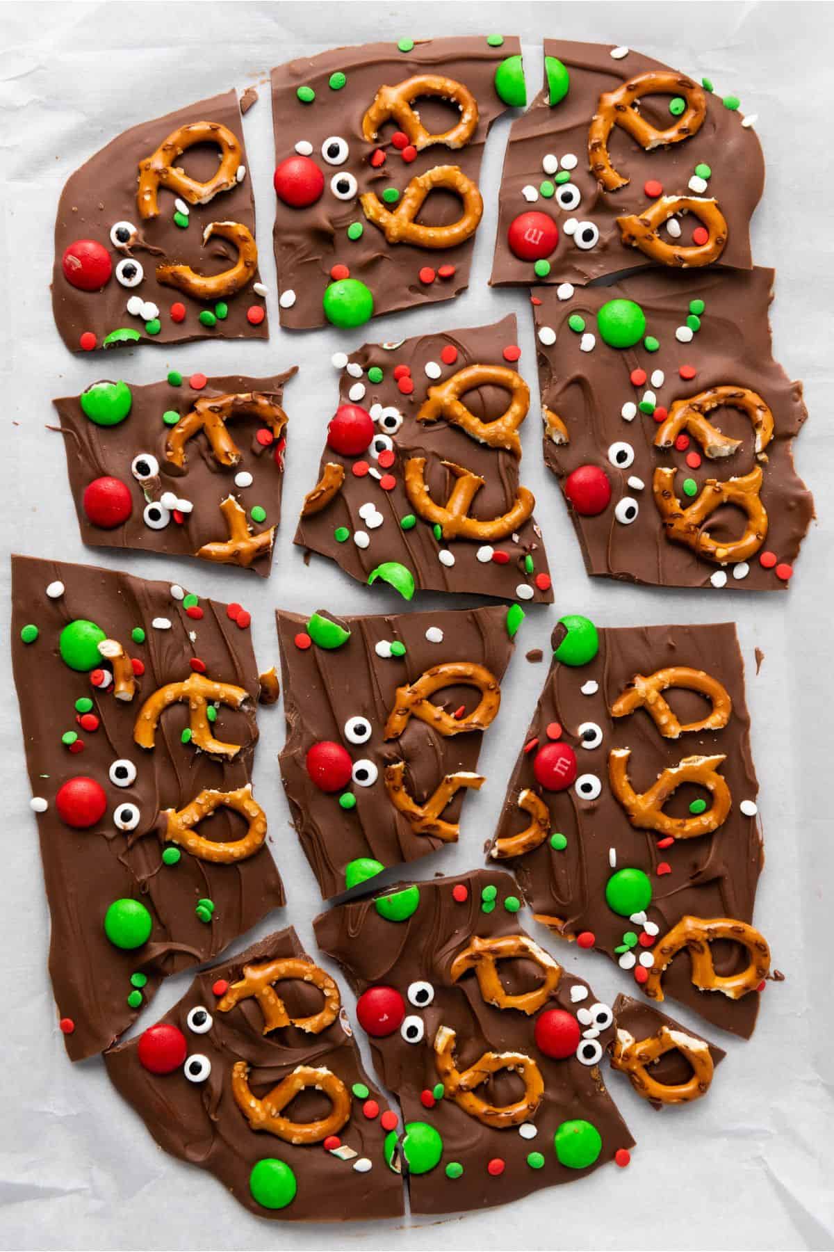 Christmas chocolate bark on parchment paper being cracked into pieces.