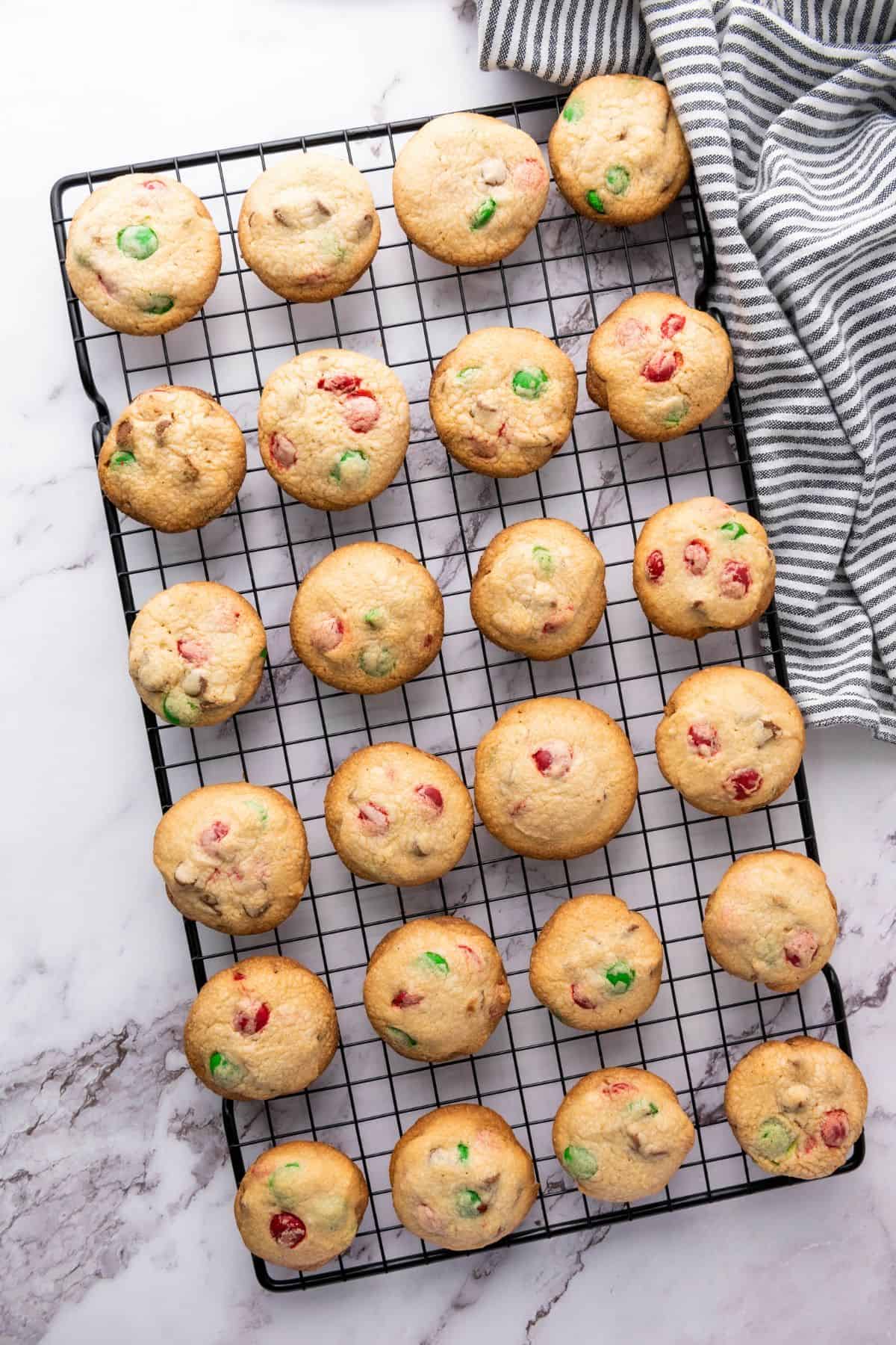 Freshly baked Christmas M&M cookies cooling on a wire rack.