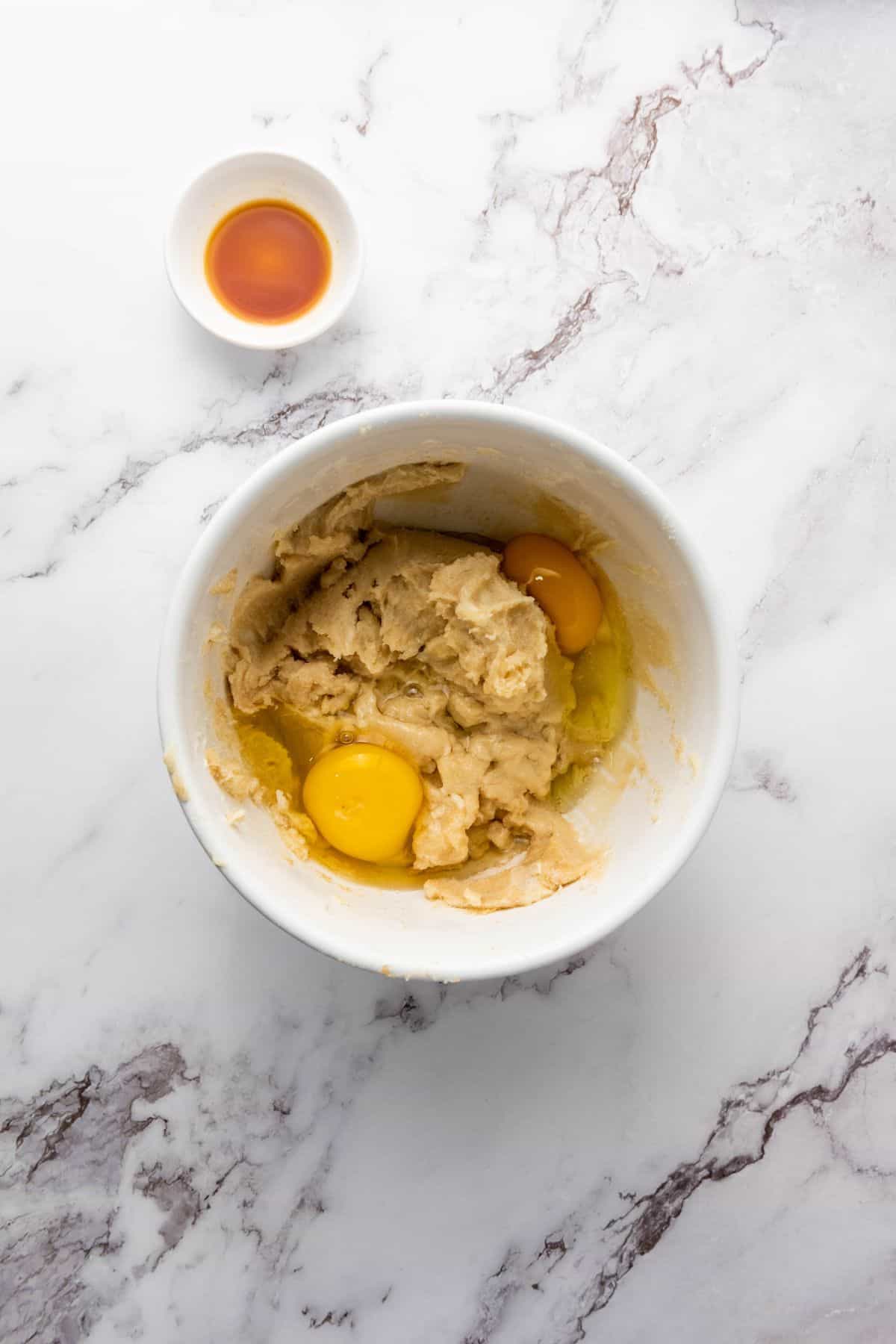 Cookie dough mixture in a bowl with ingredient on the side.