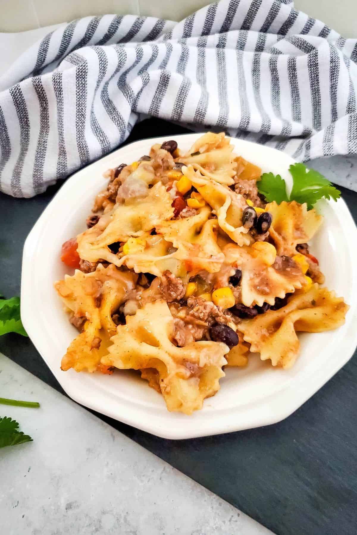 One-pan Tex-Mex pasta bake served on a plate with a table napkin placed beside it.