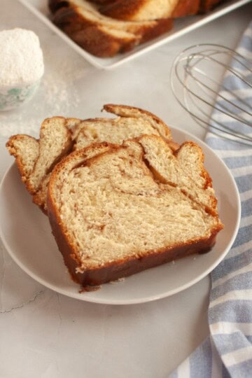 Sliced homemade sourdough cinnamon babka served on a small plate, placed on a cloth-covered surface.