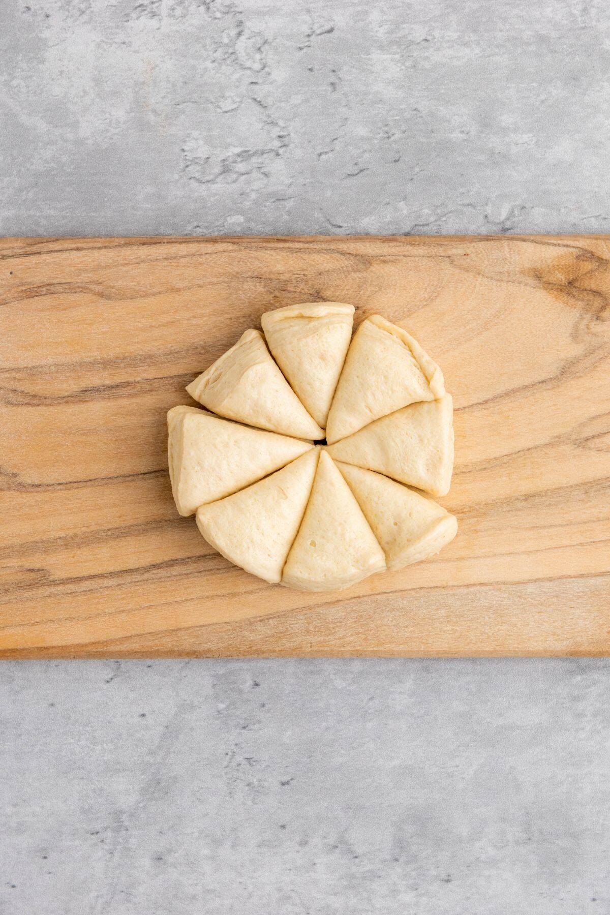 Dough pieces being shaped into small triangles on a surface for Mini Cranberry Brie Pull-Apart Bread.