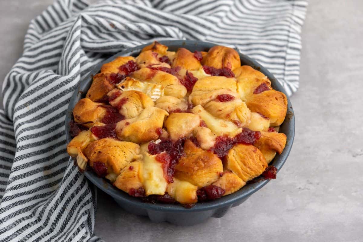 Mini pull-apart bread served on a plate with a cloth beside it.